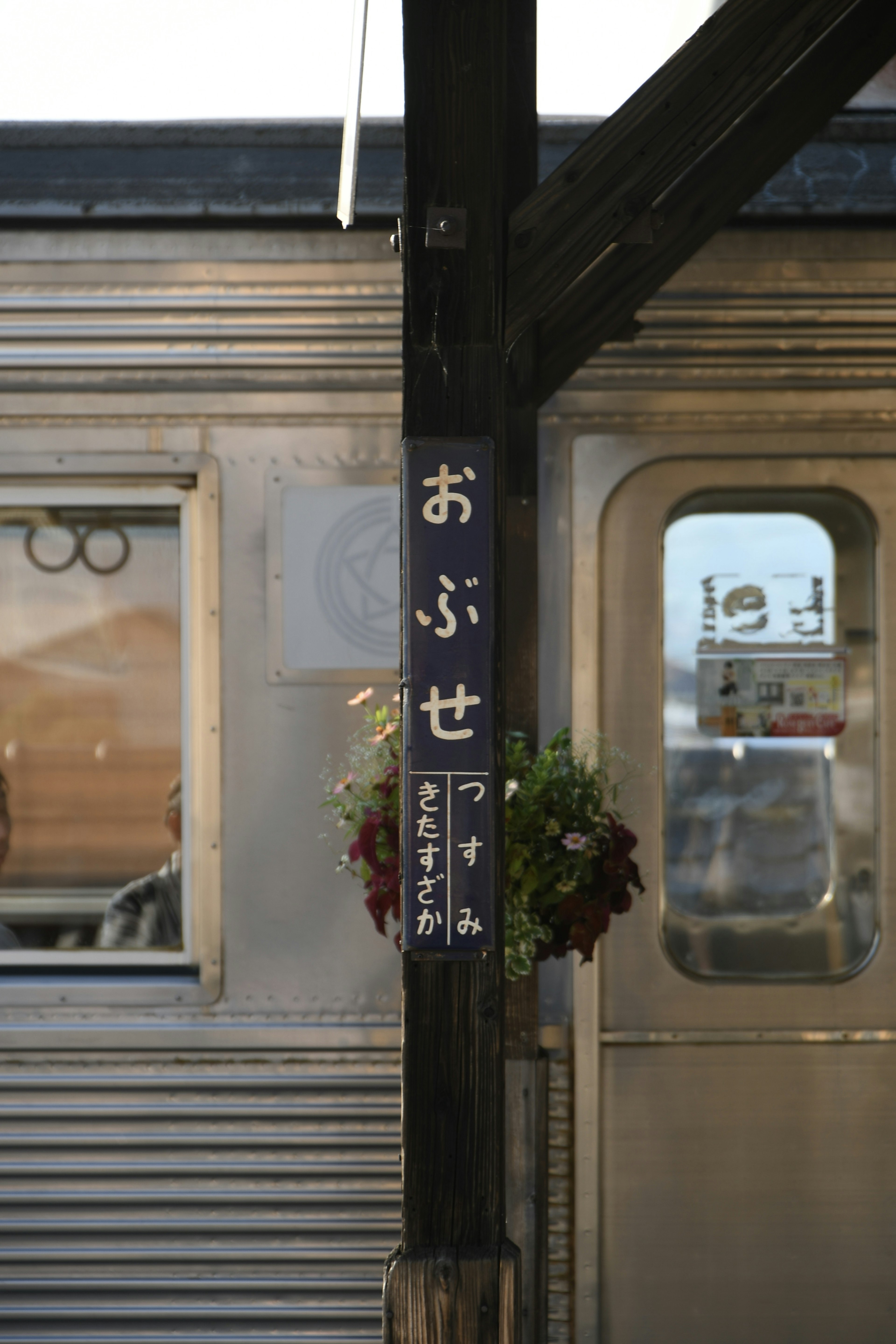 Panneau de la gare d'Obuse avec une porte de train en arrière-plan