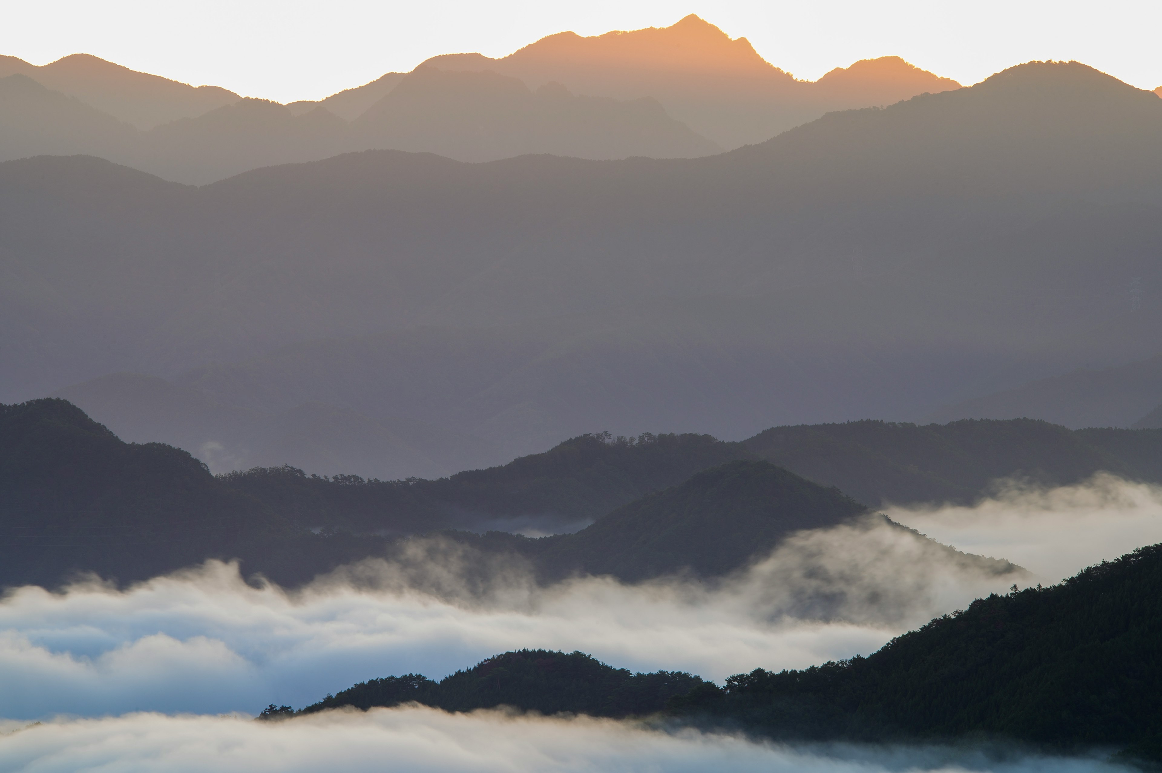 霧に包まれた山々と朝日を浴びる山のシルエット