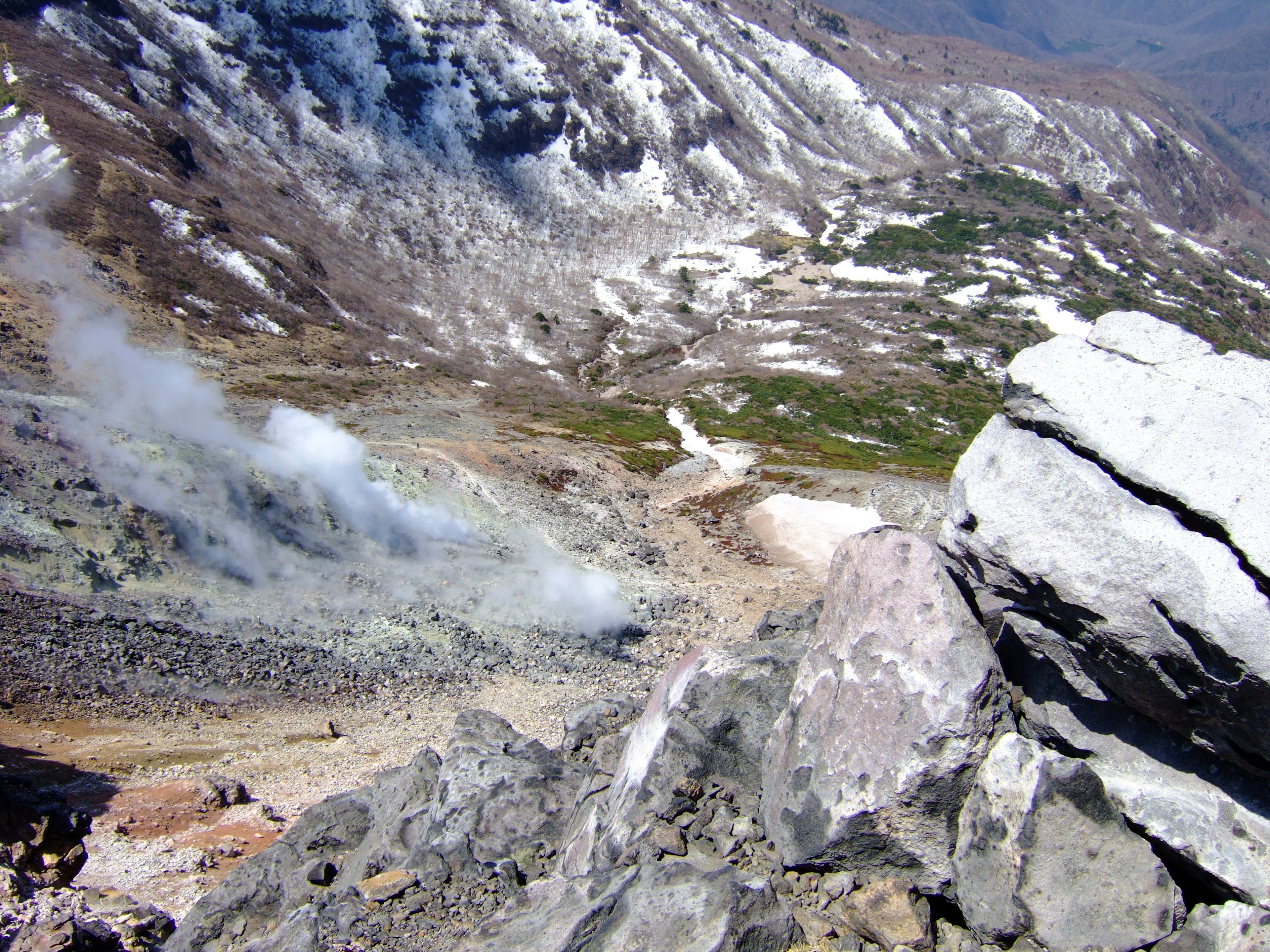 Paisaje montañoso con humo volcánico y rocas