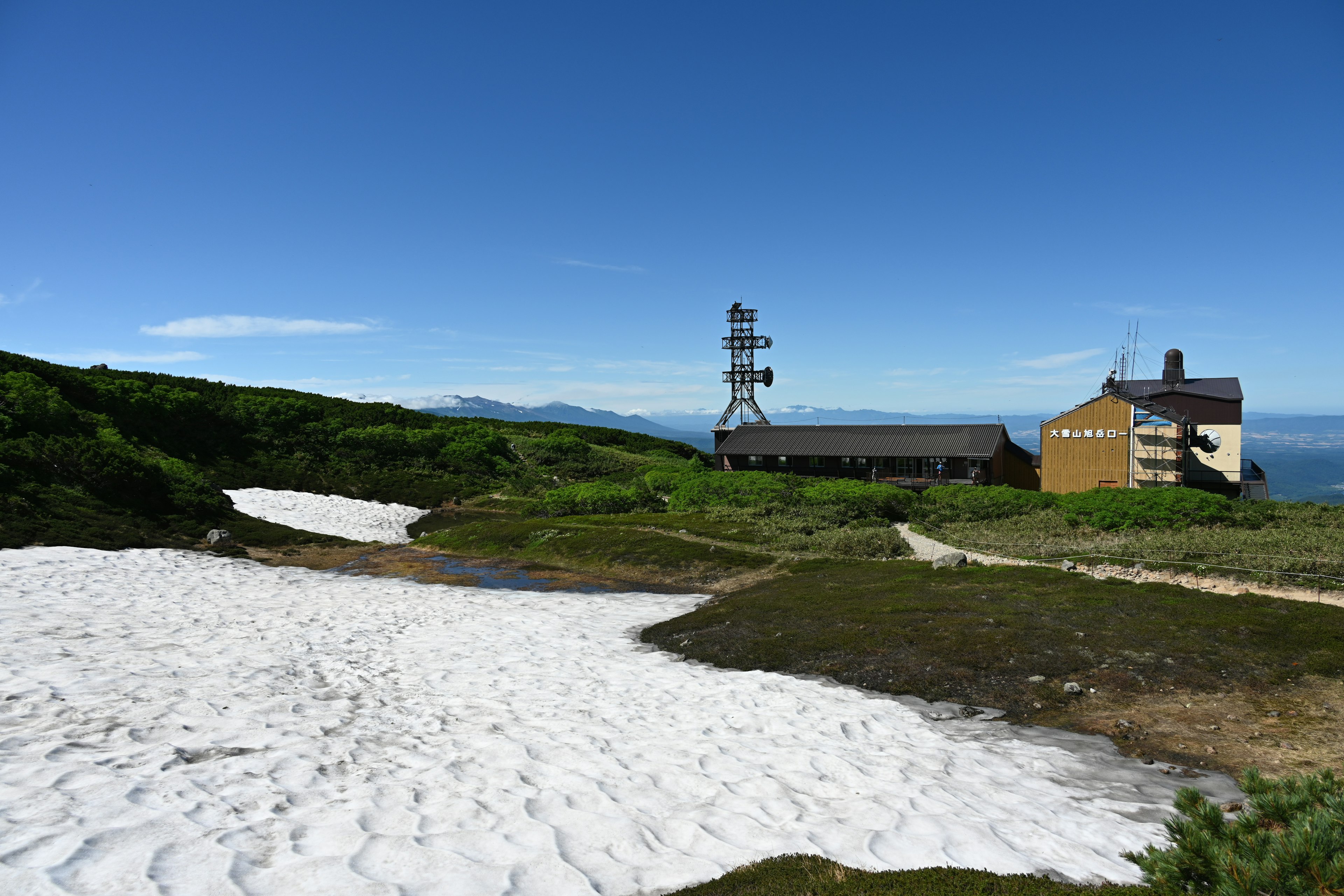 A landscape featuring a snow-covered area and a communication tower