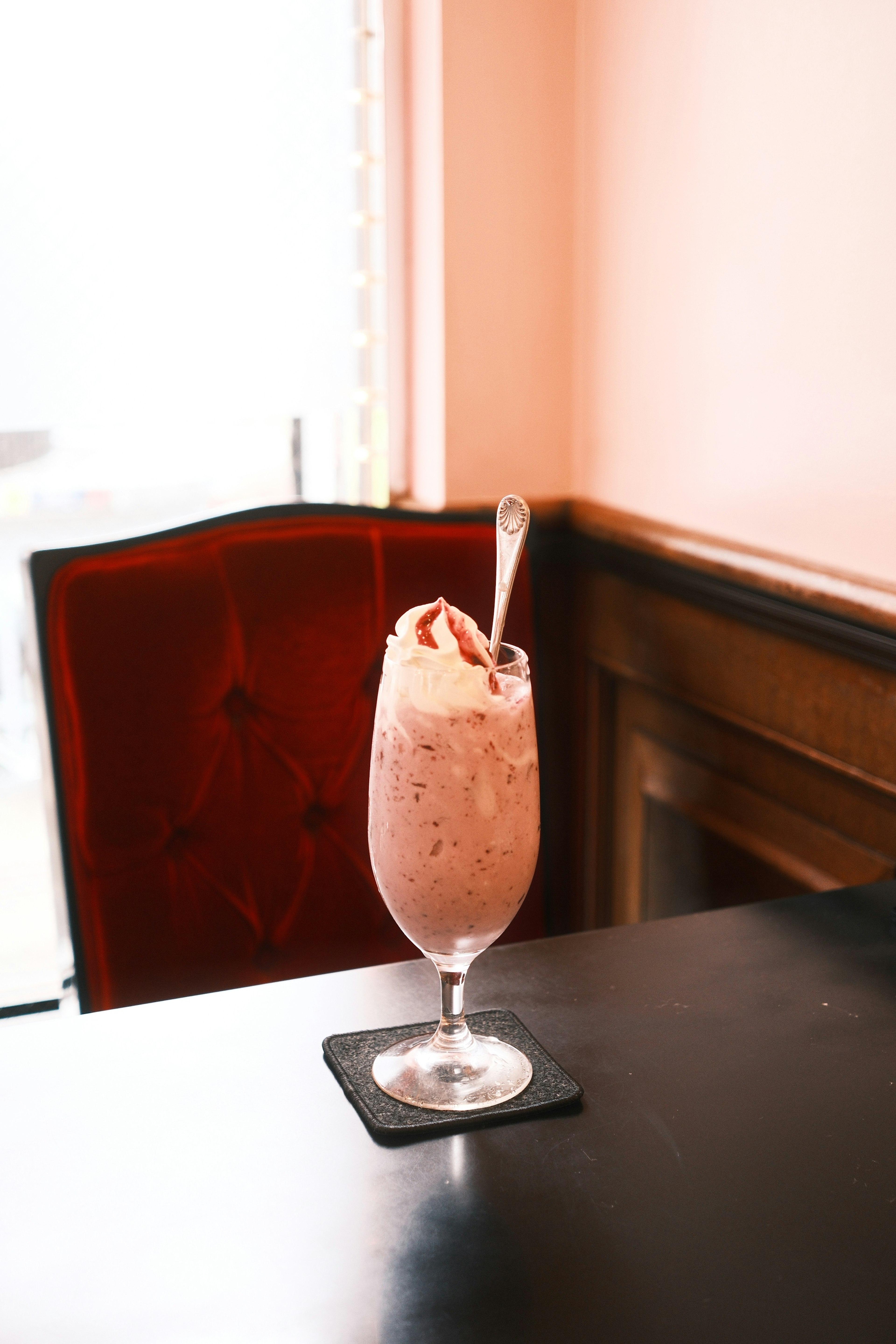 Verre de milkshake à la fraise sur une table avec une chaise rouge en arrière-plan