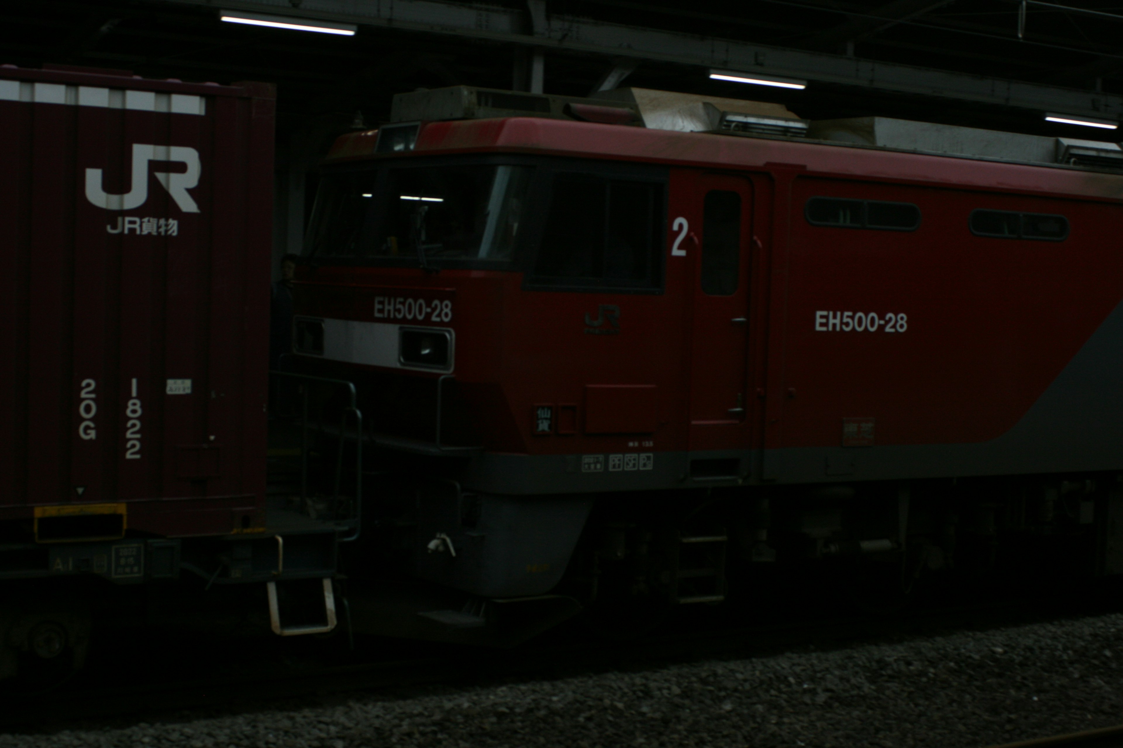 Treno merci rosso e container in stazione notturna