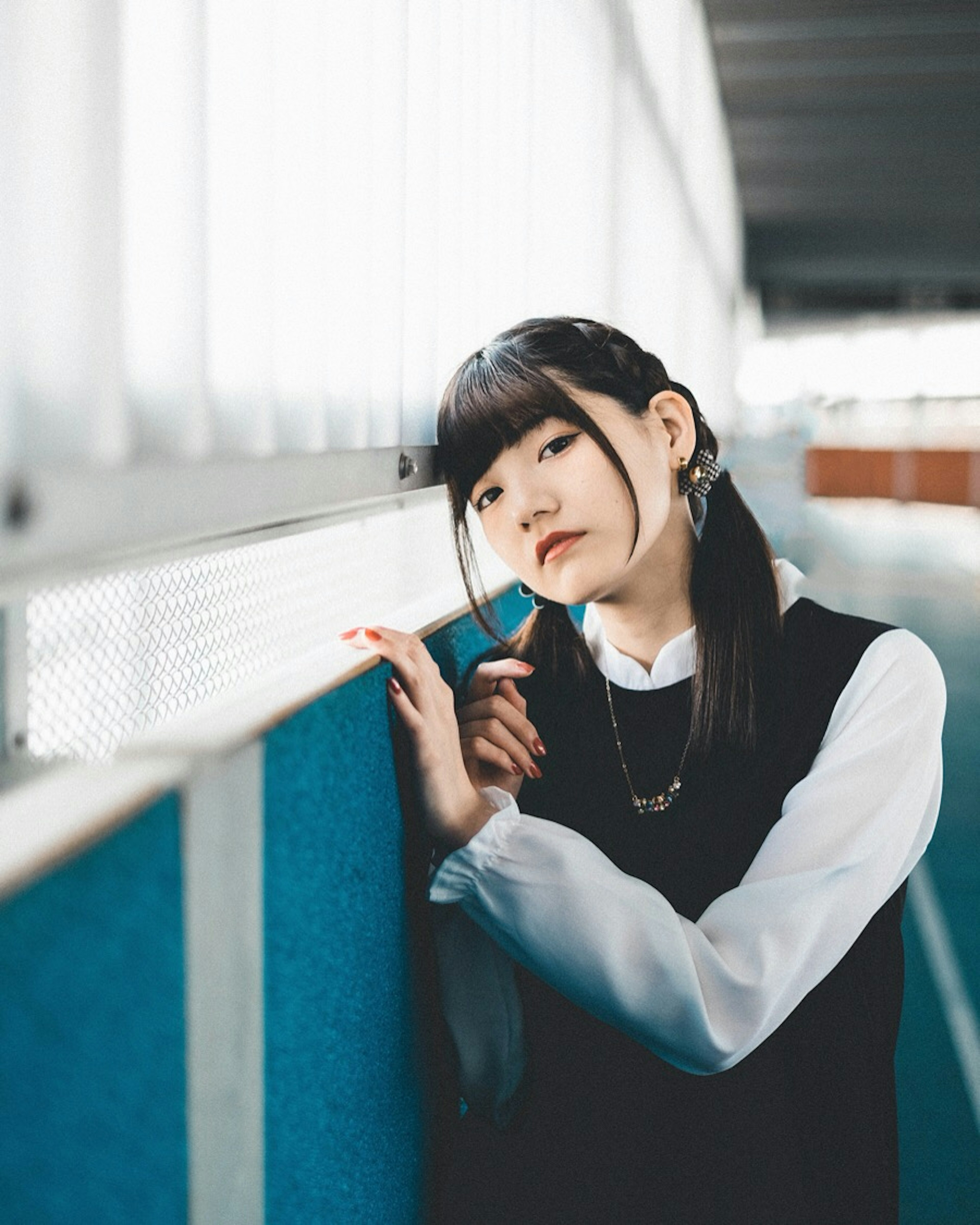 Portrait of a female student leaning against a blue wall in a school corridor