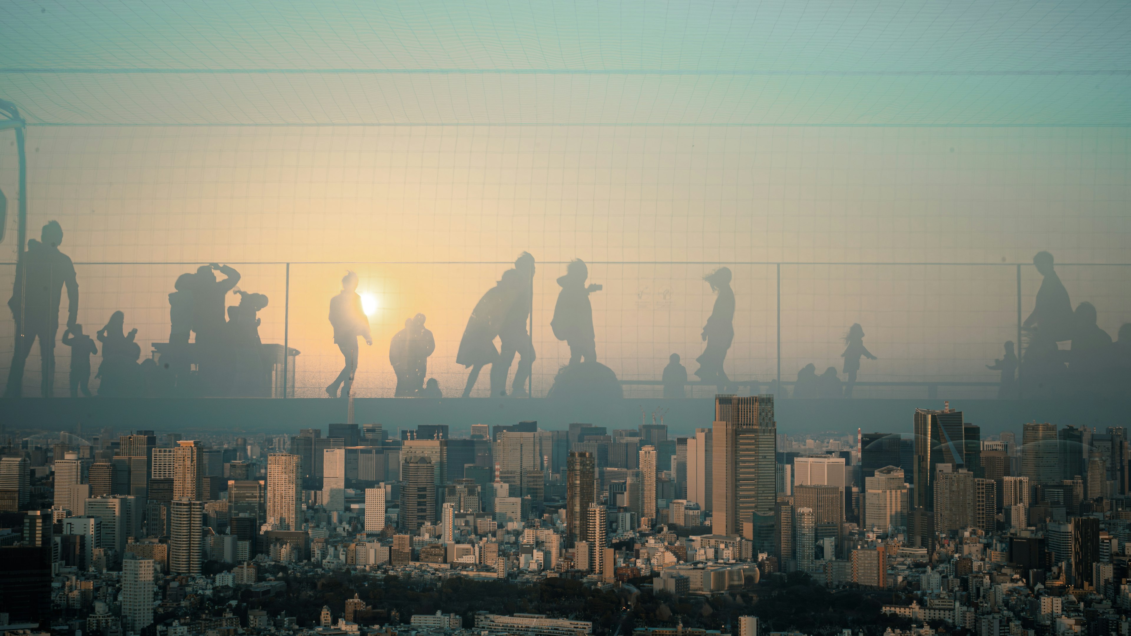 朝日を背にした人々のシルエットと都市の風景