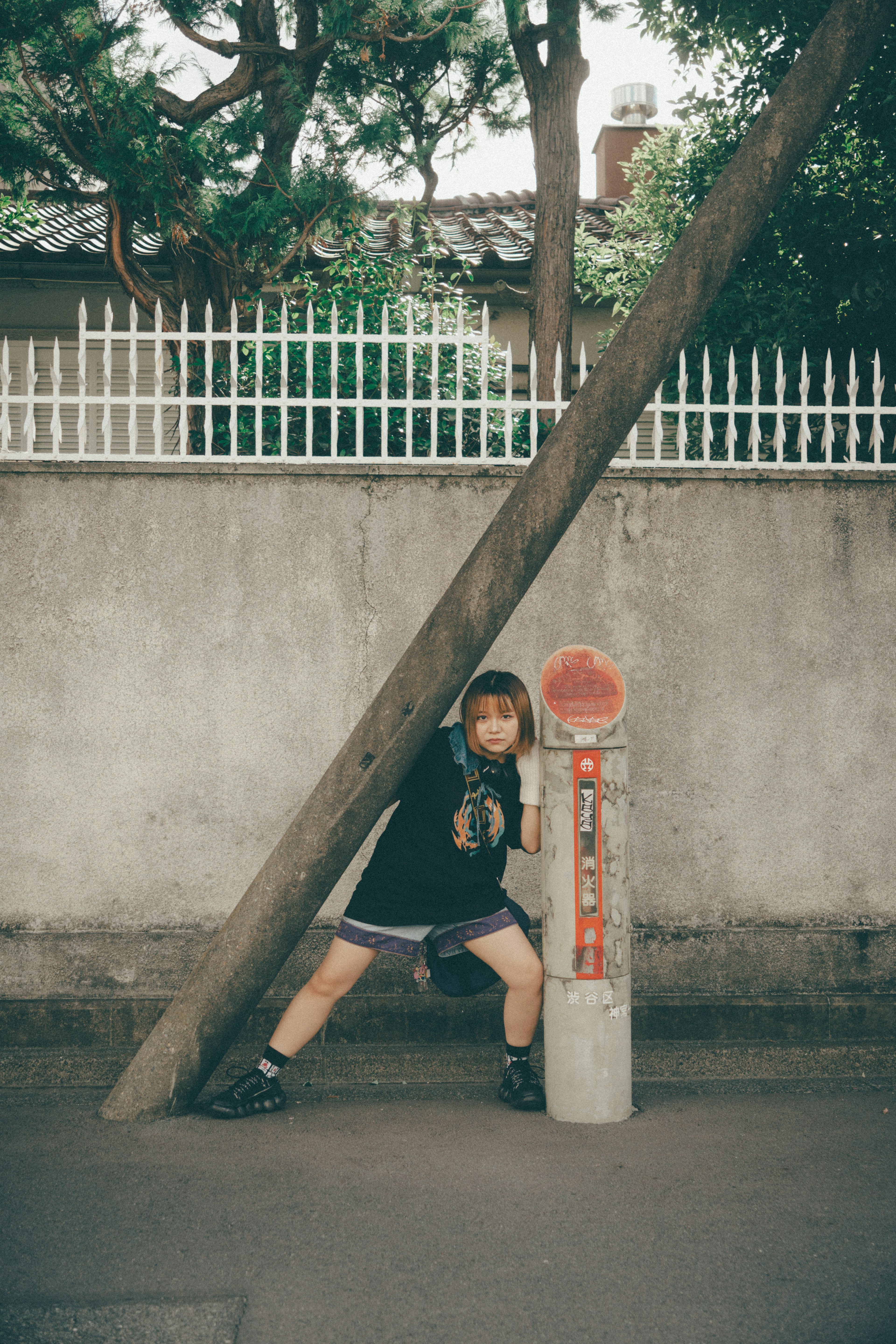 A child leaning against a wooden pole with a white fence in the background