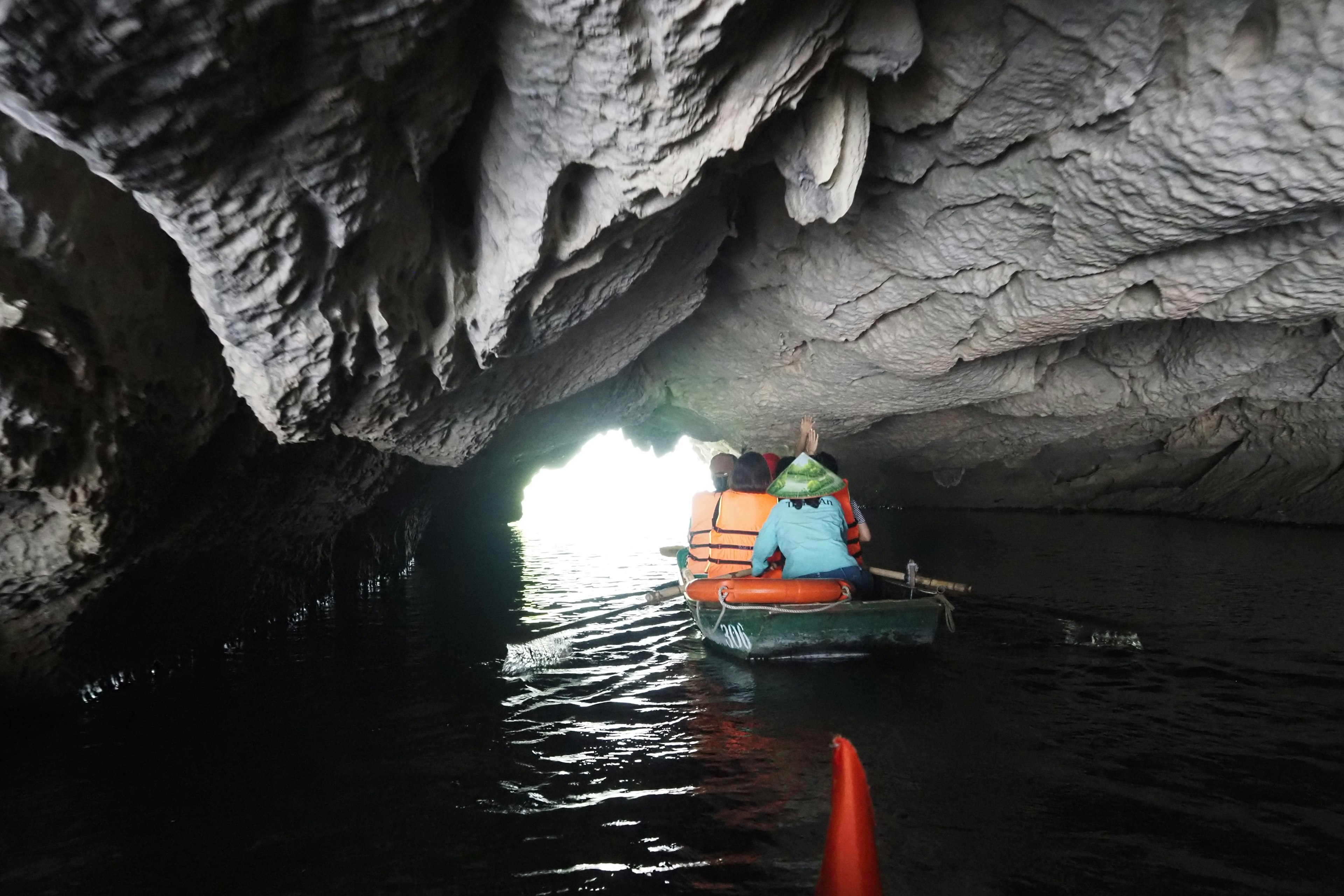 Person in a small boat inside a cave with a light tunnel