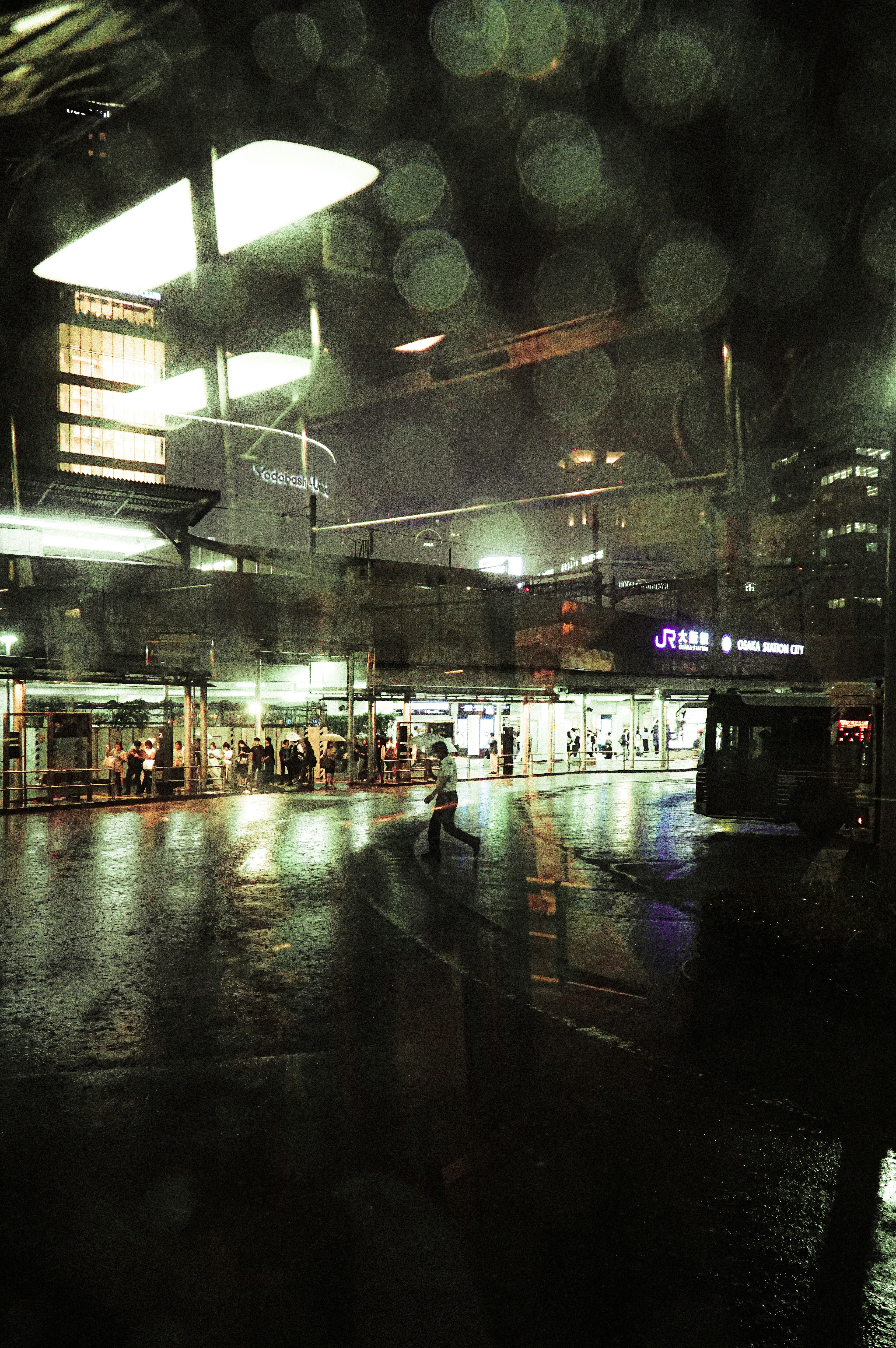 Urban scene in rain blurred lights and people traffic