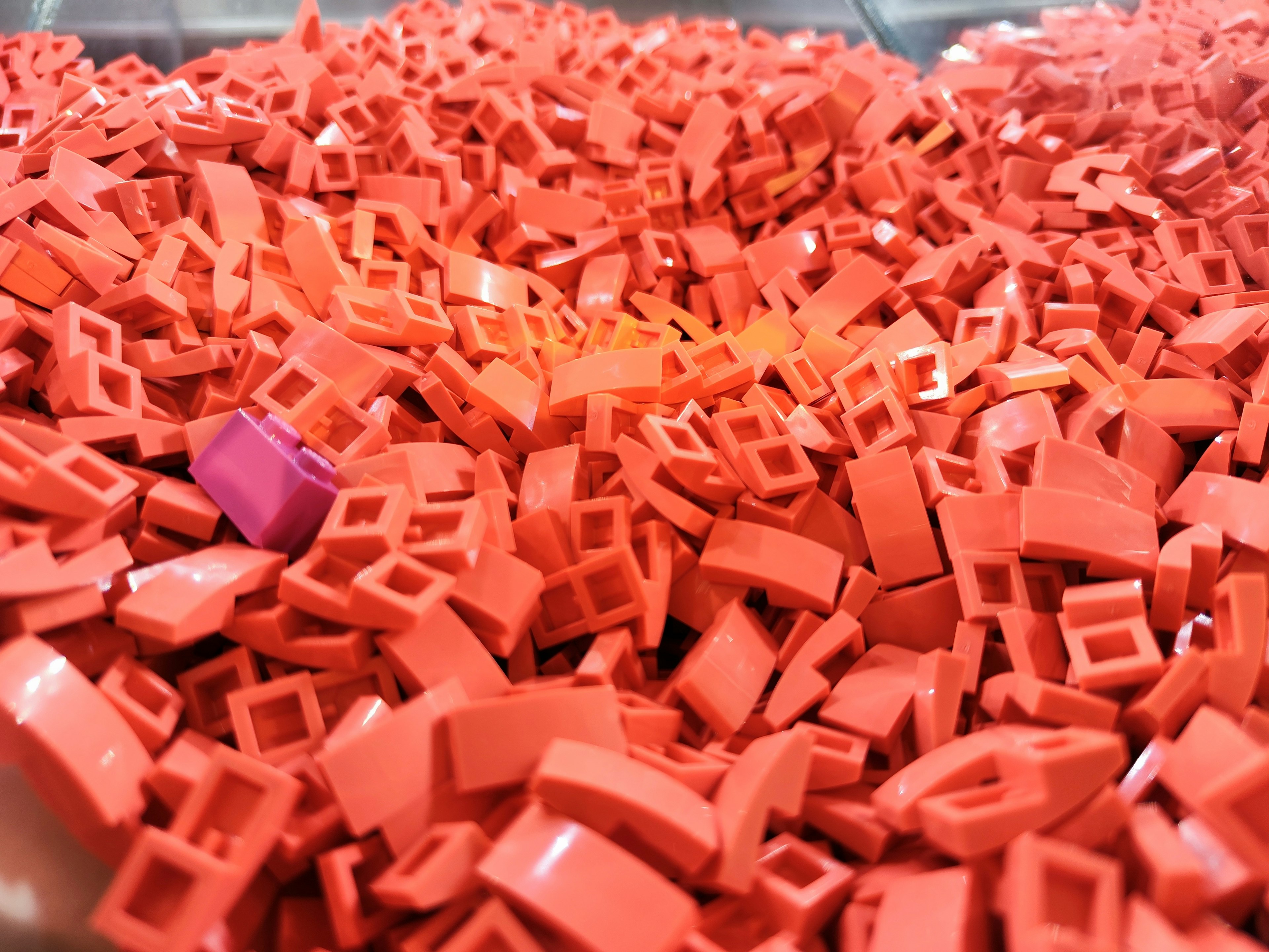 A pile of red plastic building blocks with a few purple pieces