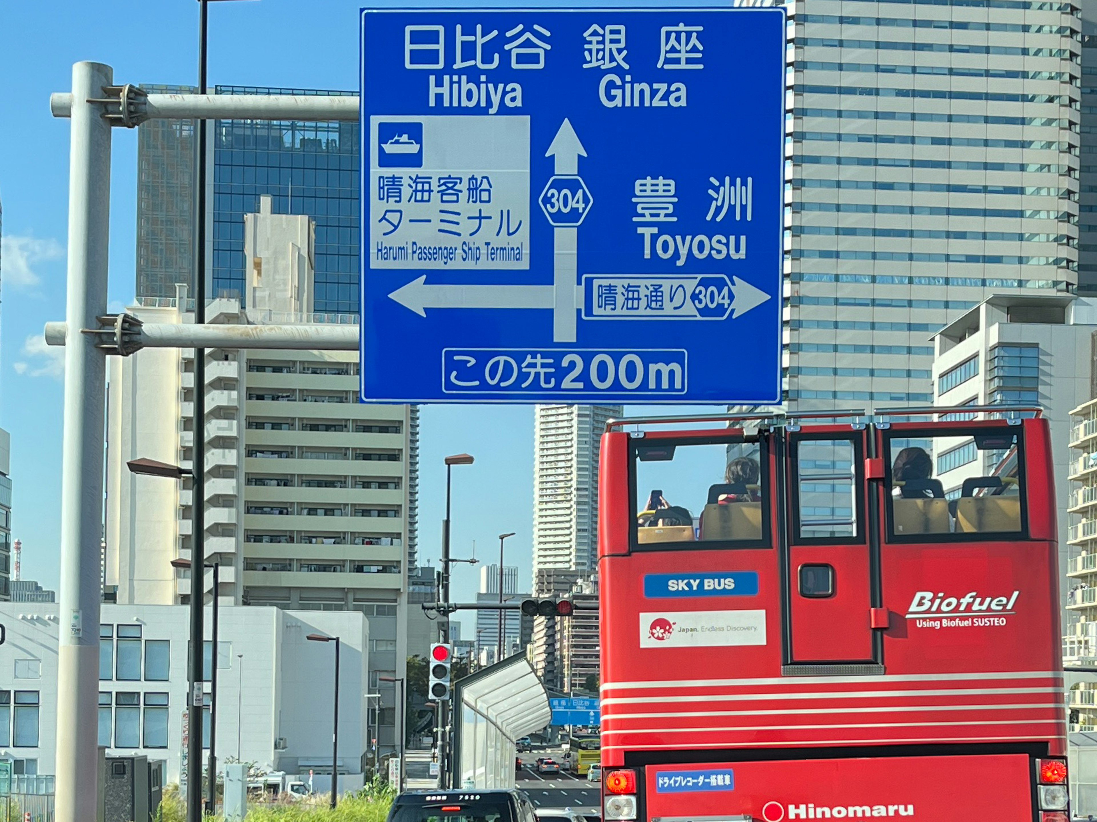 Roter Bus, der an einer städtischen Landschaft mit japanischen Verkehrsschildern vorbeifährt