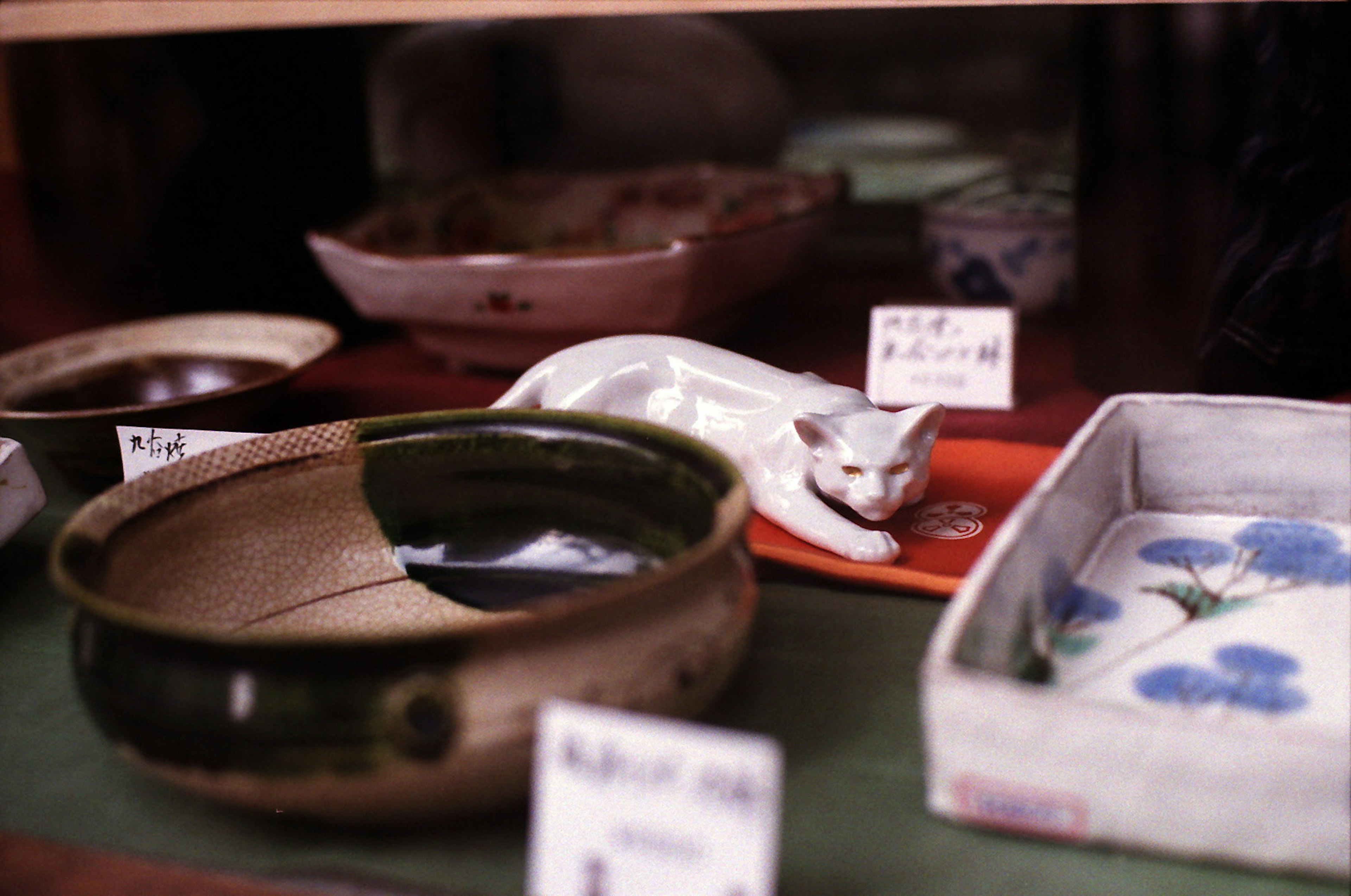 Vitrine présentant de la poterie et une figurine de chat