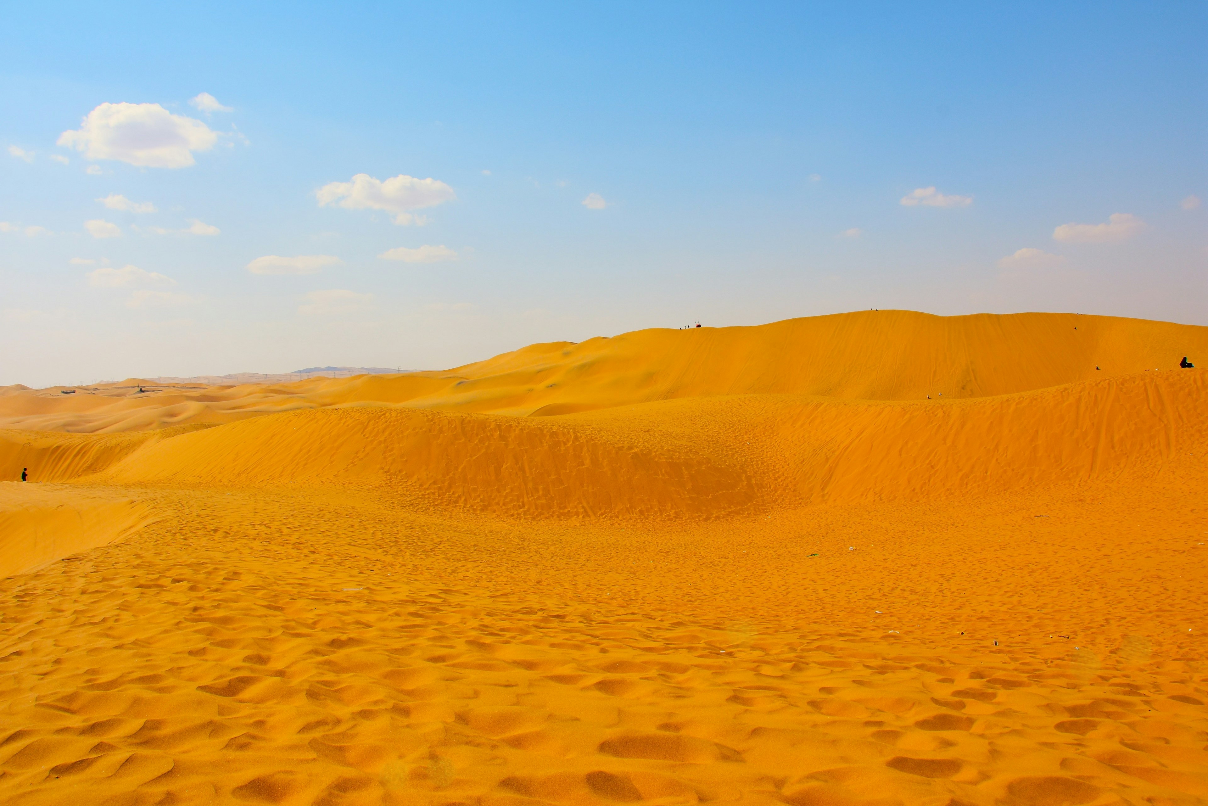 Weite orangefarbene Sanddünen unter einem blauen Himmel