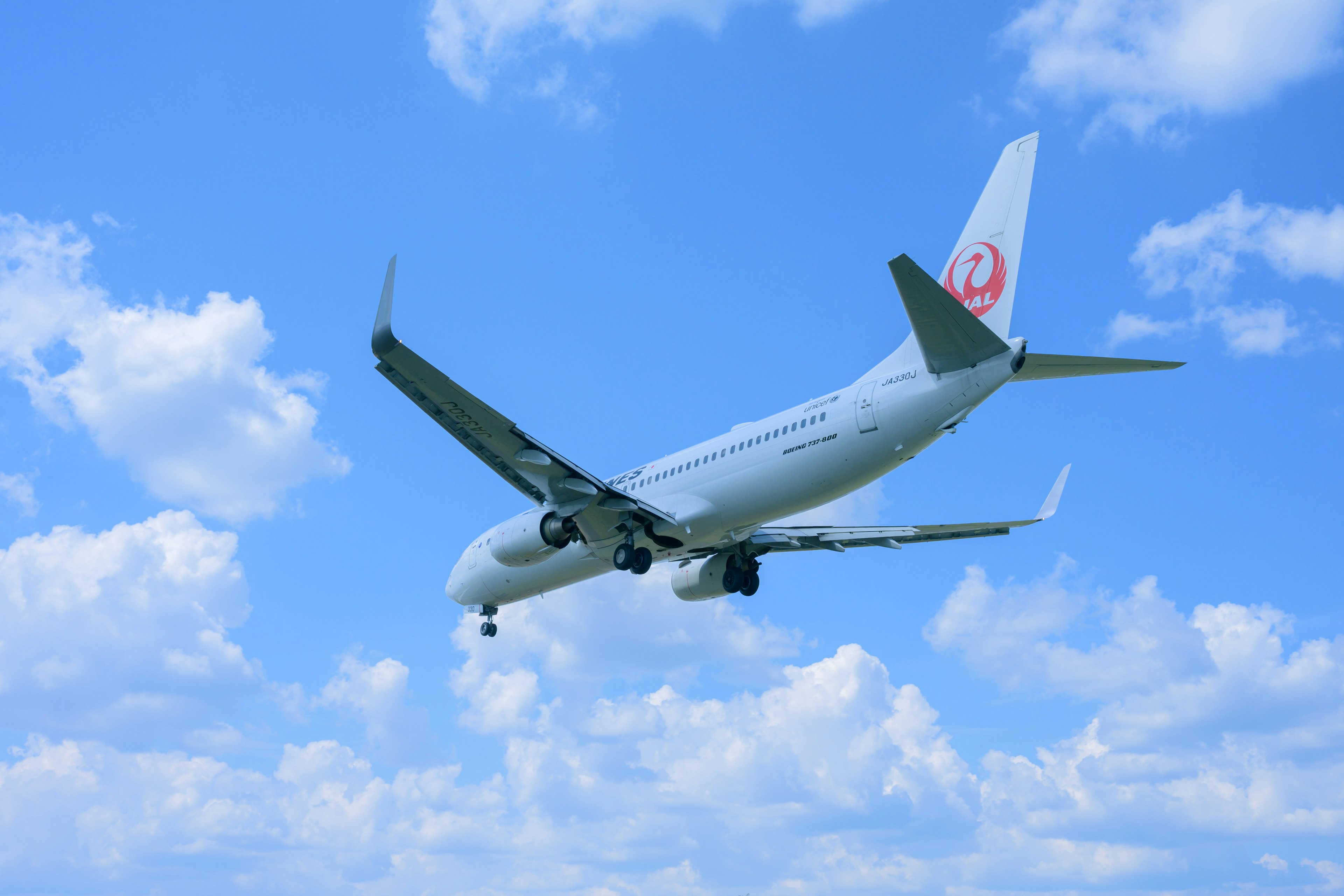 Avión de pasajeros de Japan Airlines aterrizando contra un cielo azul