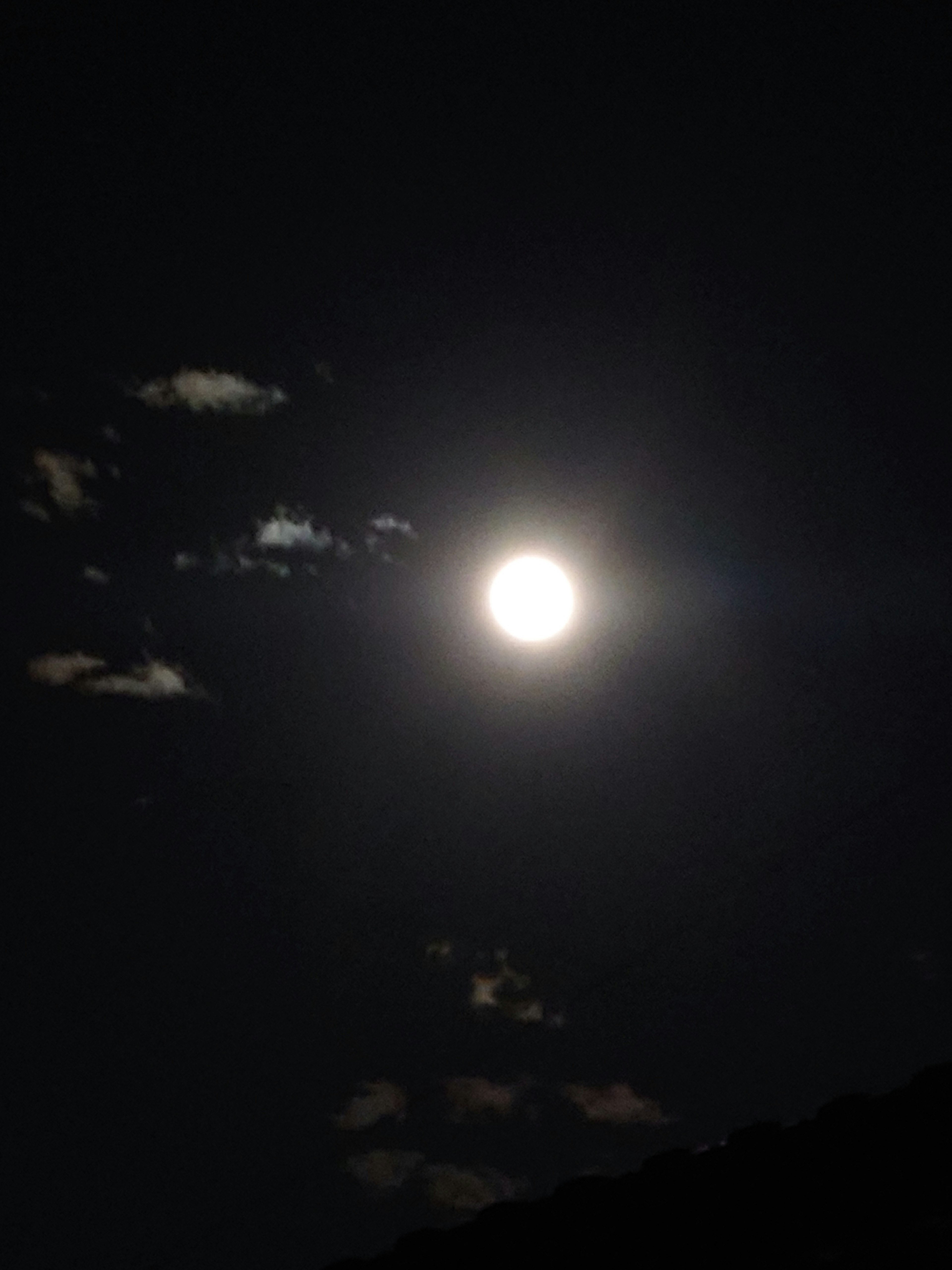 Luna llena brillante en un cielo oscuro con nubes dispersas