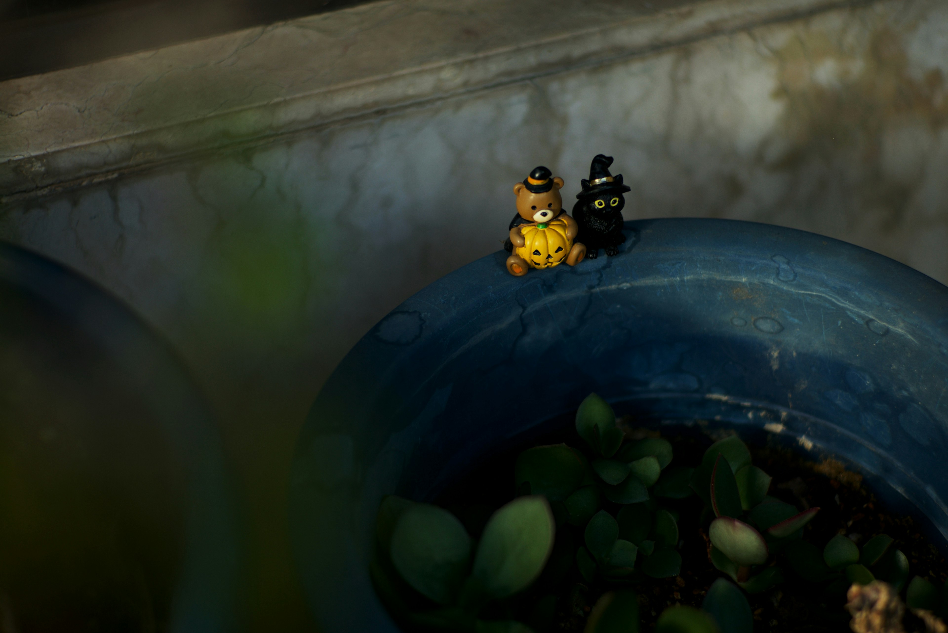 Small yellow and black figurines sitting on the edge of a blue pot