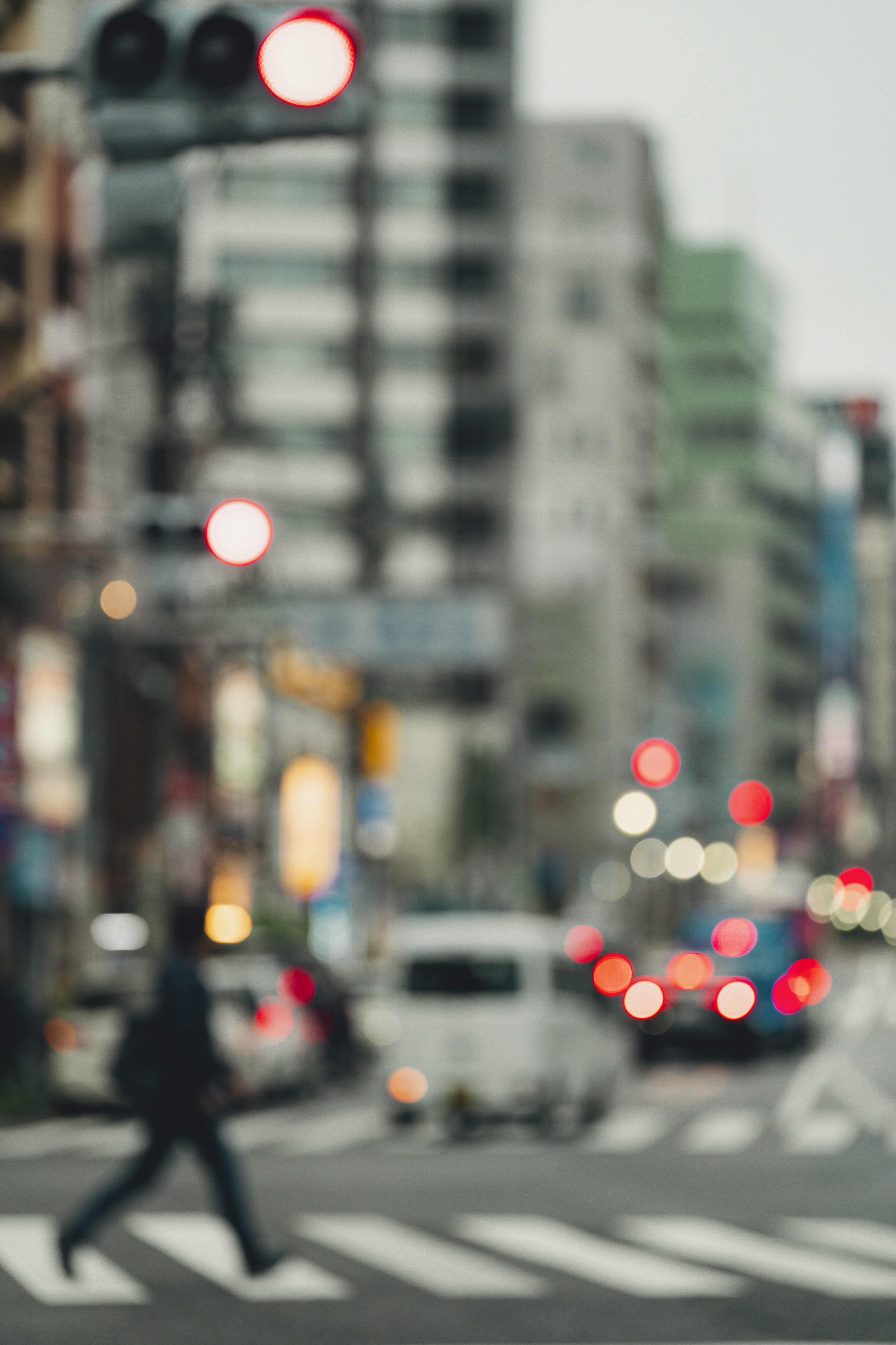 Blurred city intersection with pedestrian and red traffic lights