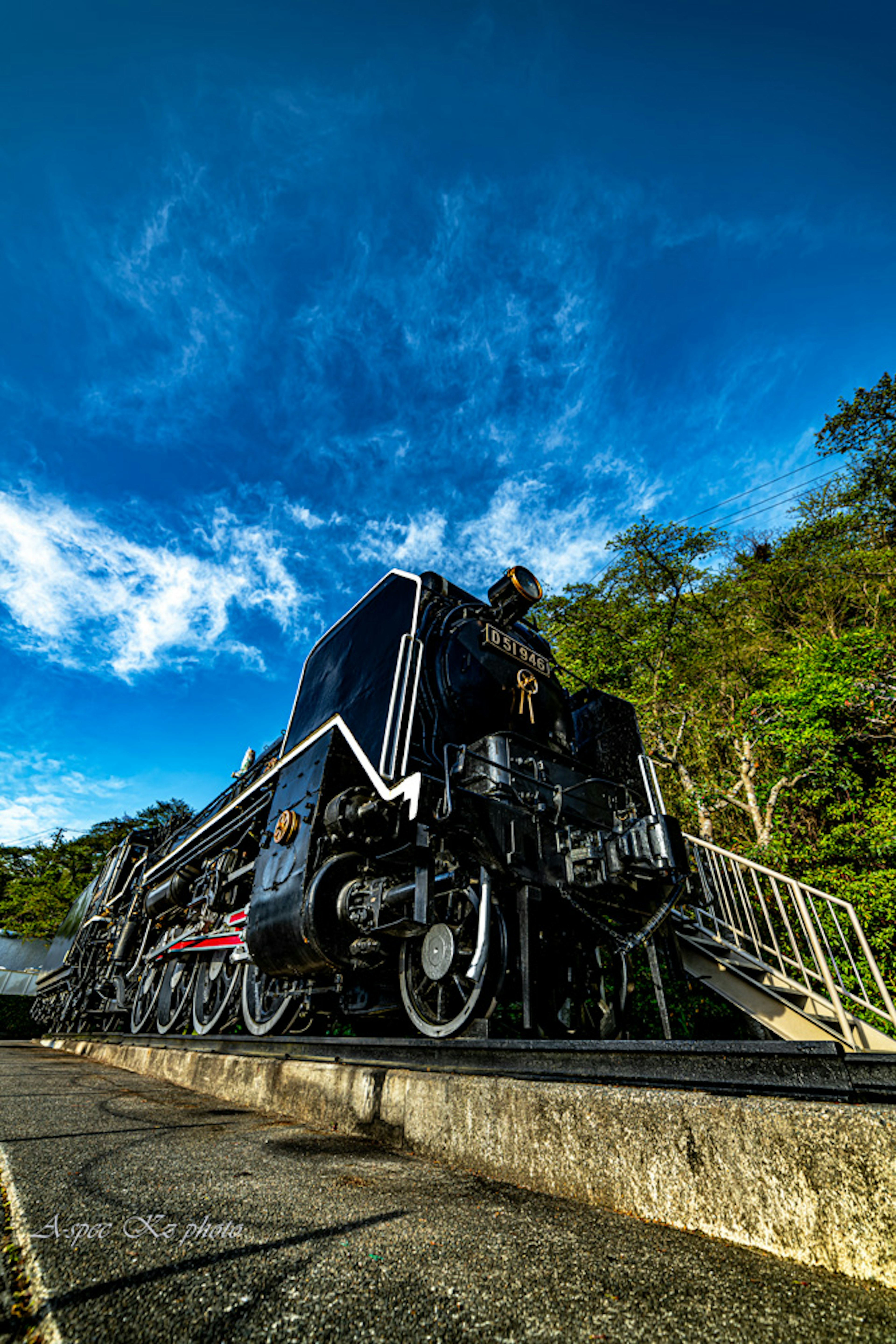 Locomotora de vapor negra estacionada bajo un cielo azul