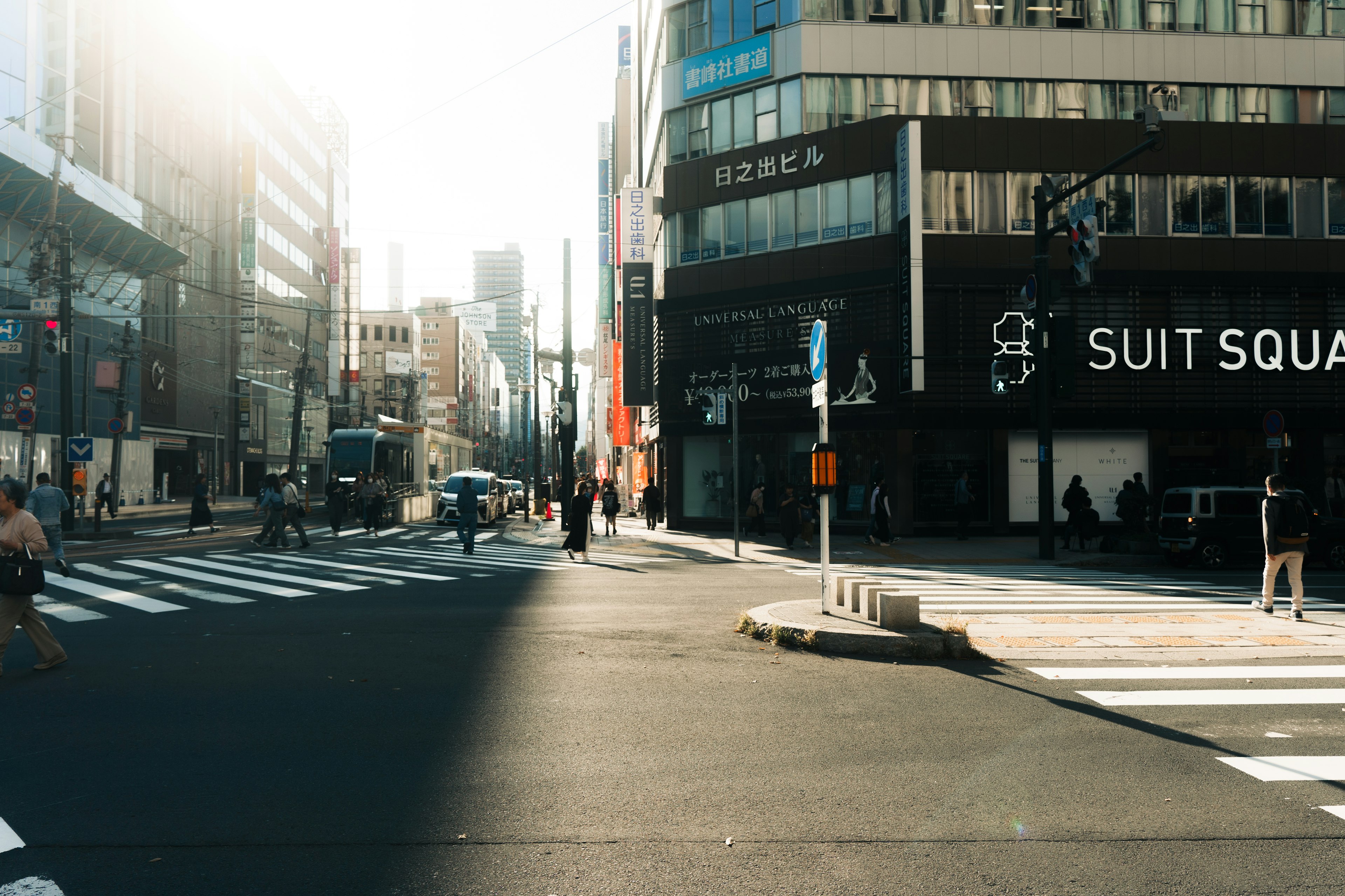 Urban intersection with people and vehicles in bright sunlight