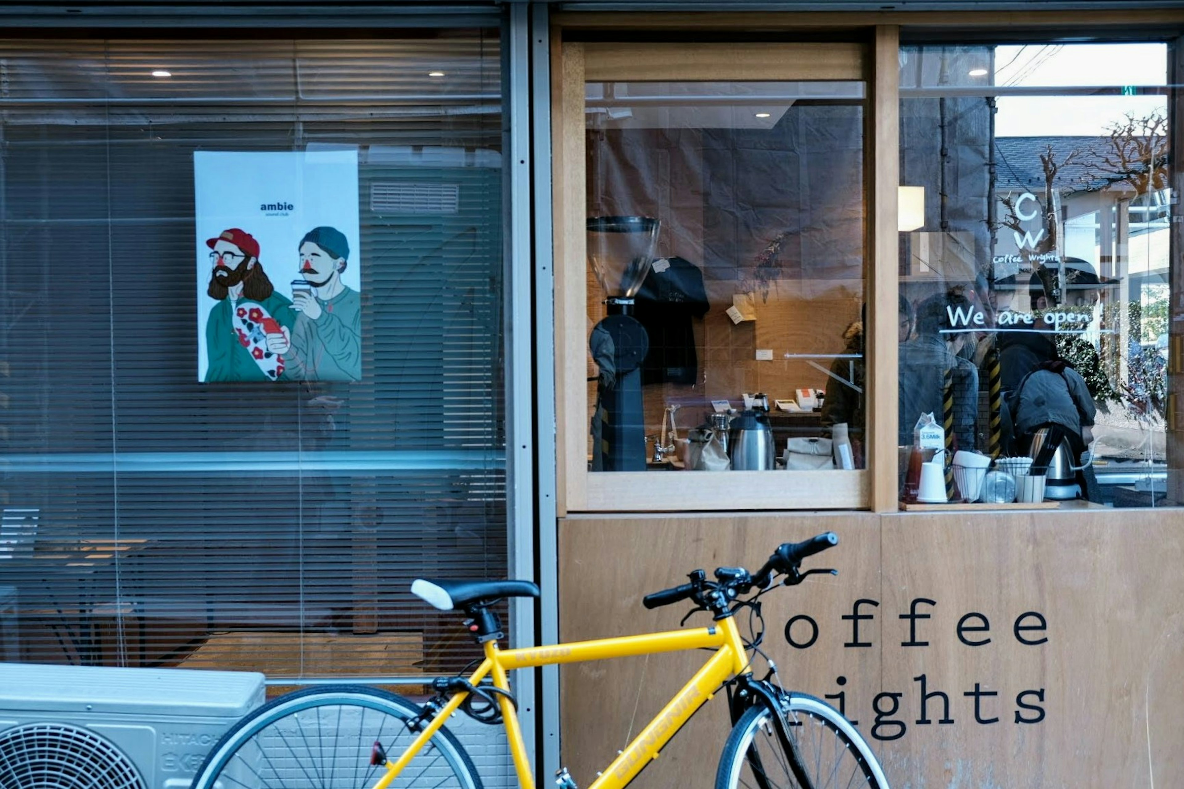 Extérieur d'un café avec un vélo jaune et une œuvre d'art dans la fenêtre