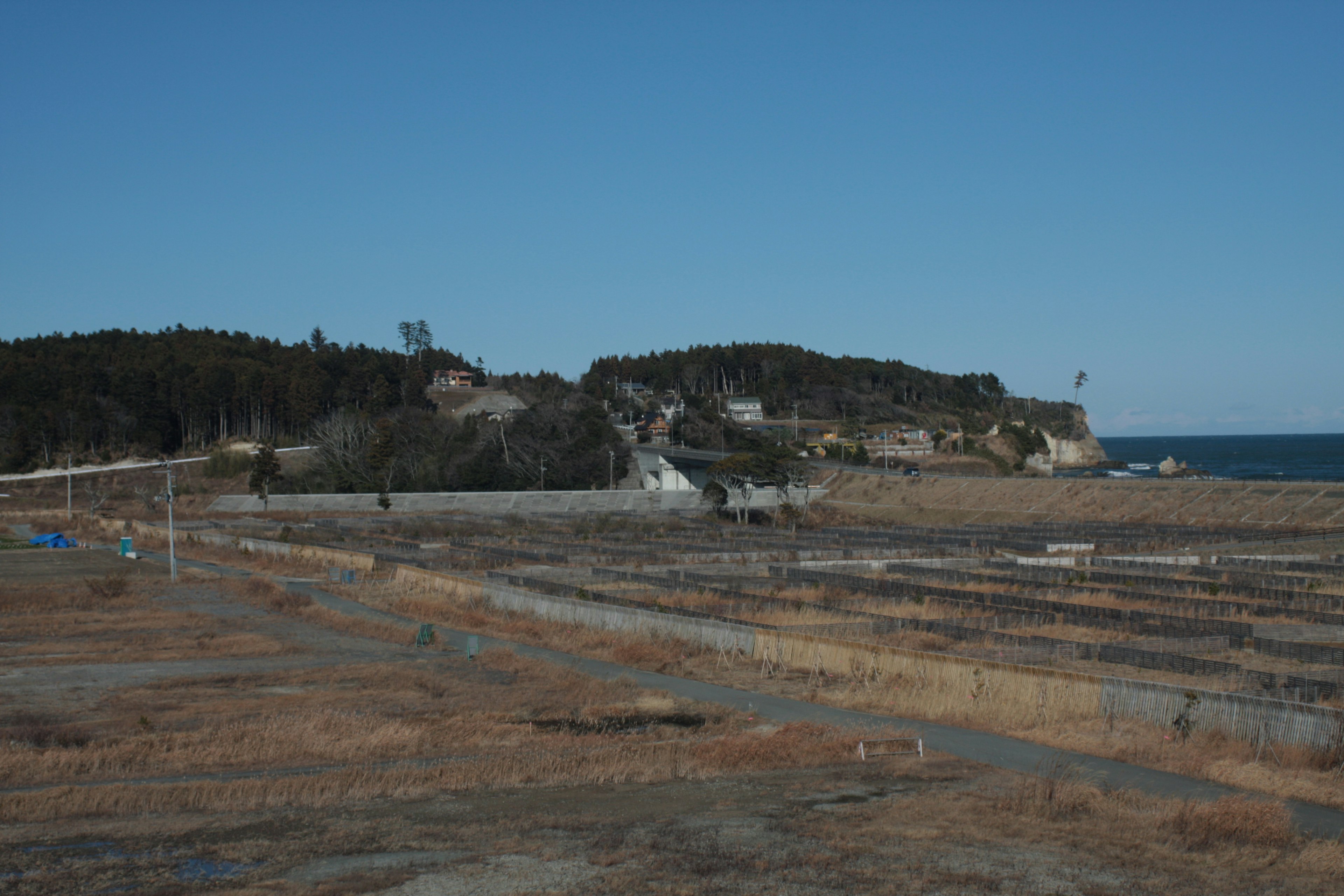 Paesaggio costiero con terra arida e edifici su colline lontane