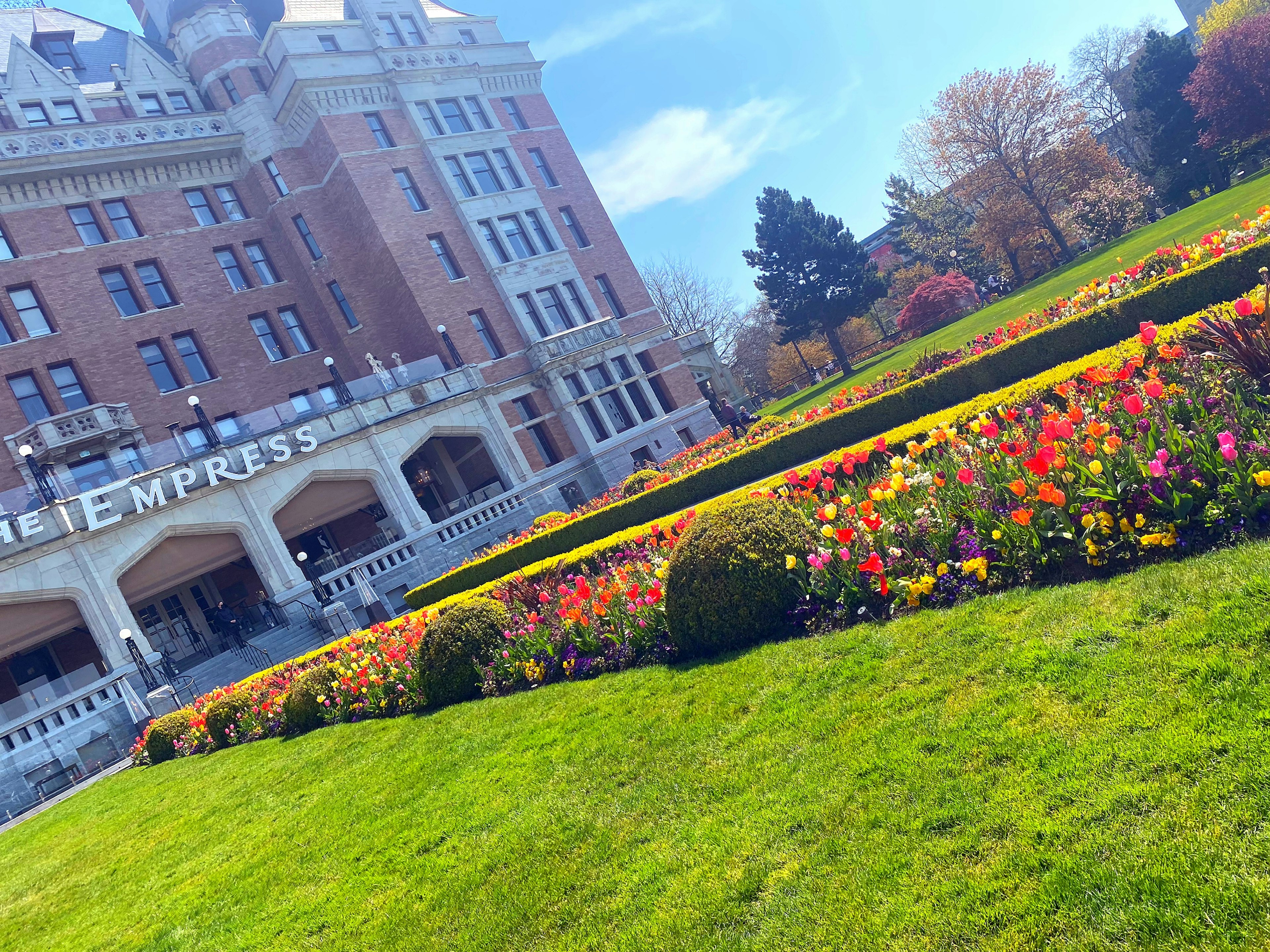 Colorful flower bed and green lawn in front of the Empress Hotel