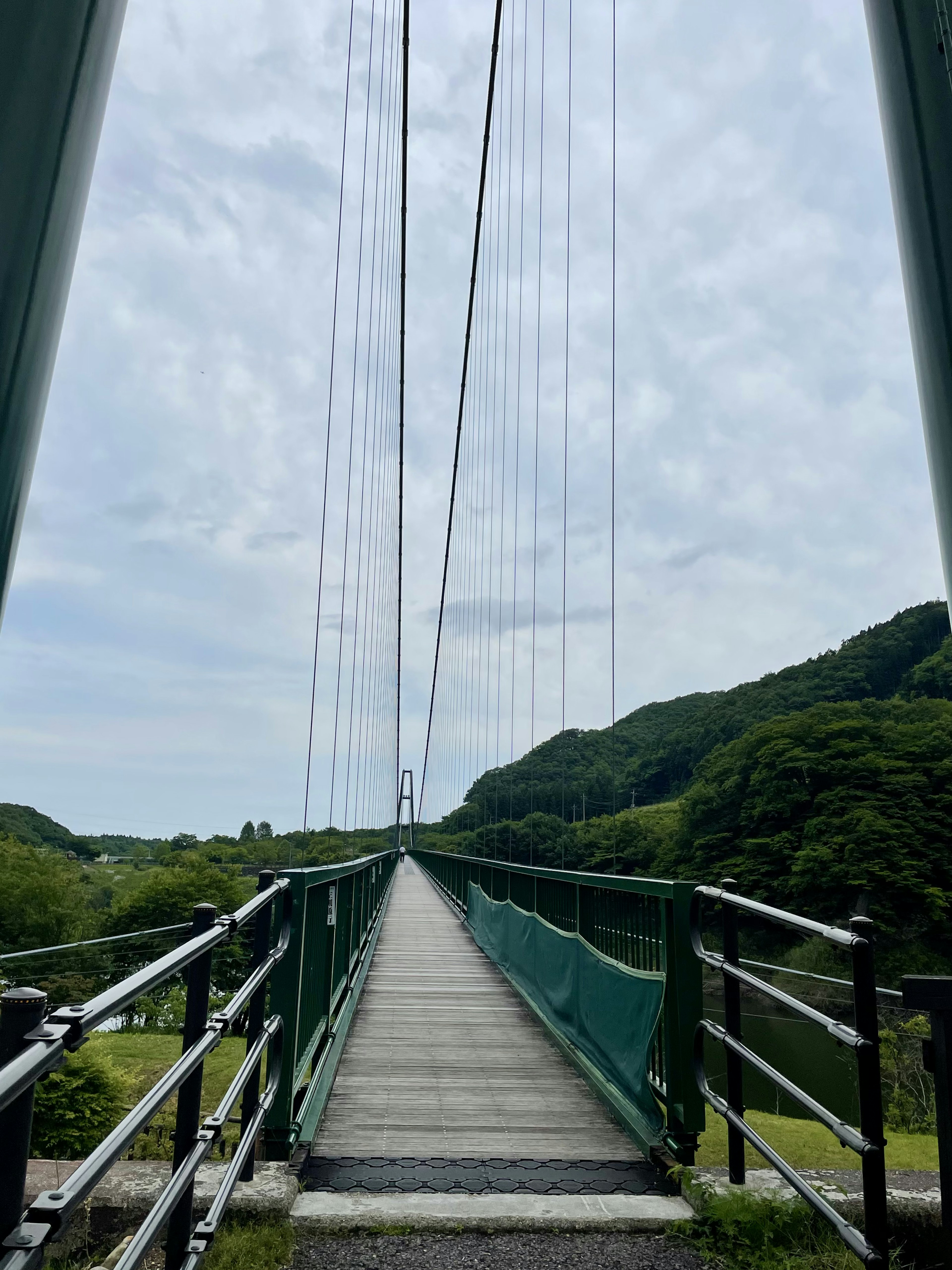 緑の山々に囲まれた吊り橋の風景 橋の上から見える空と道