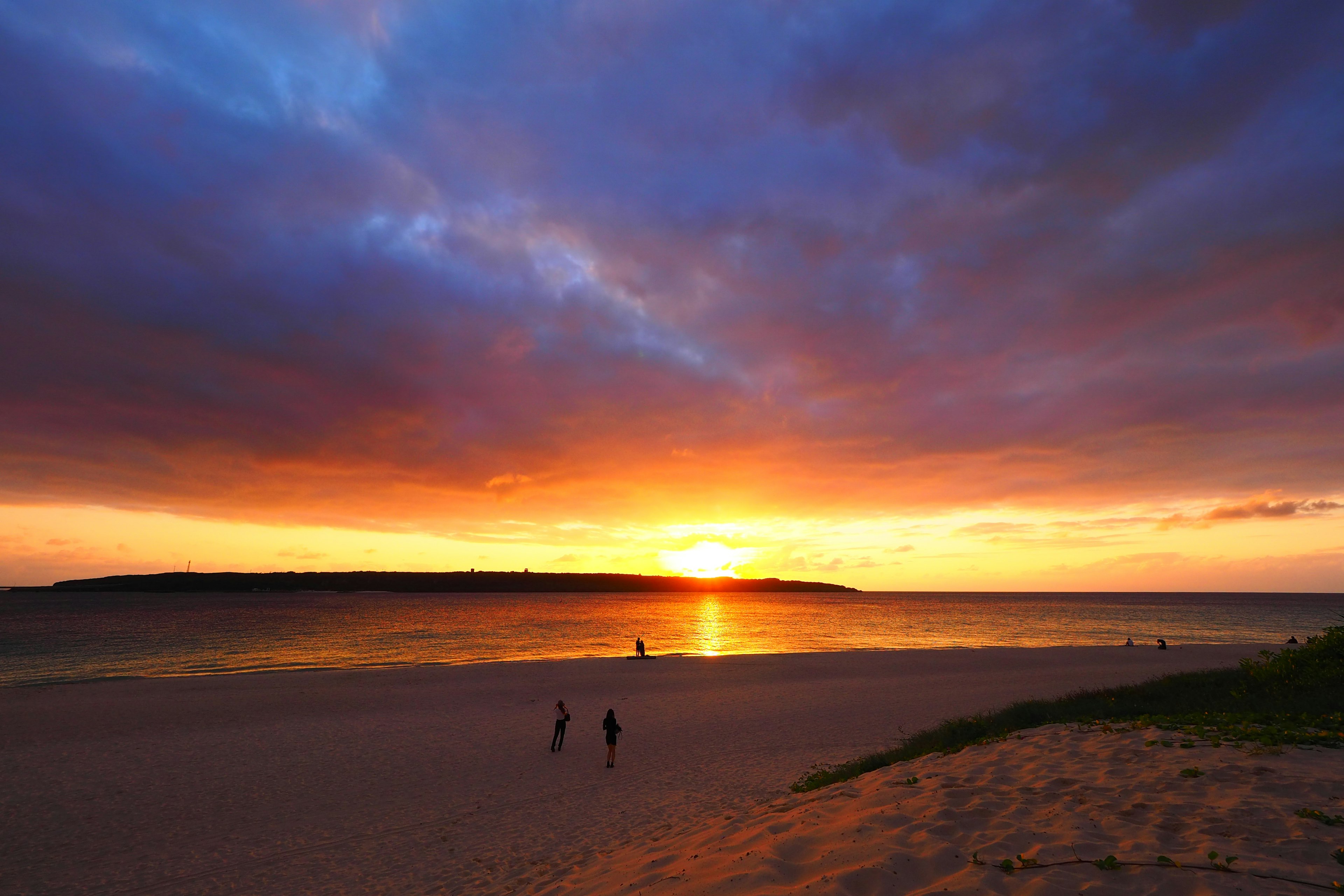 Beach scene with sunset and people walking