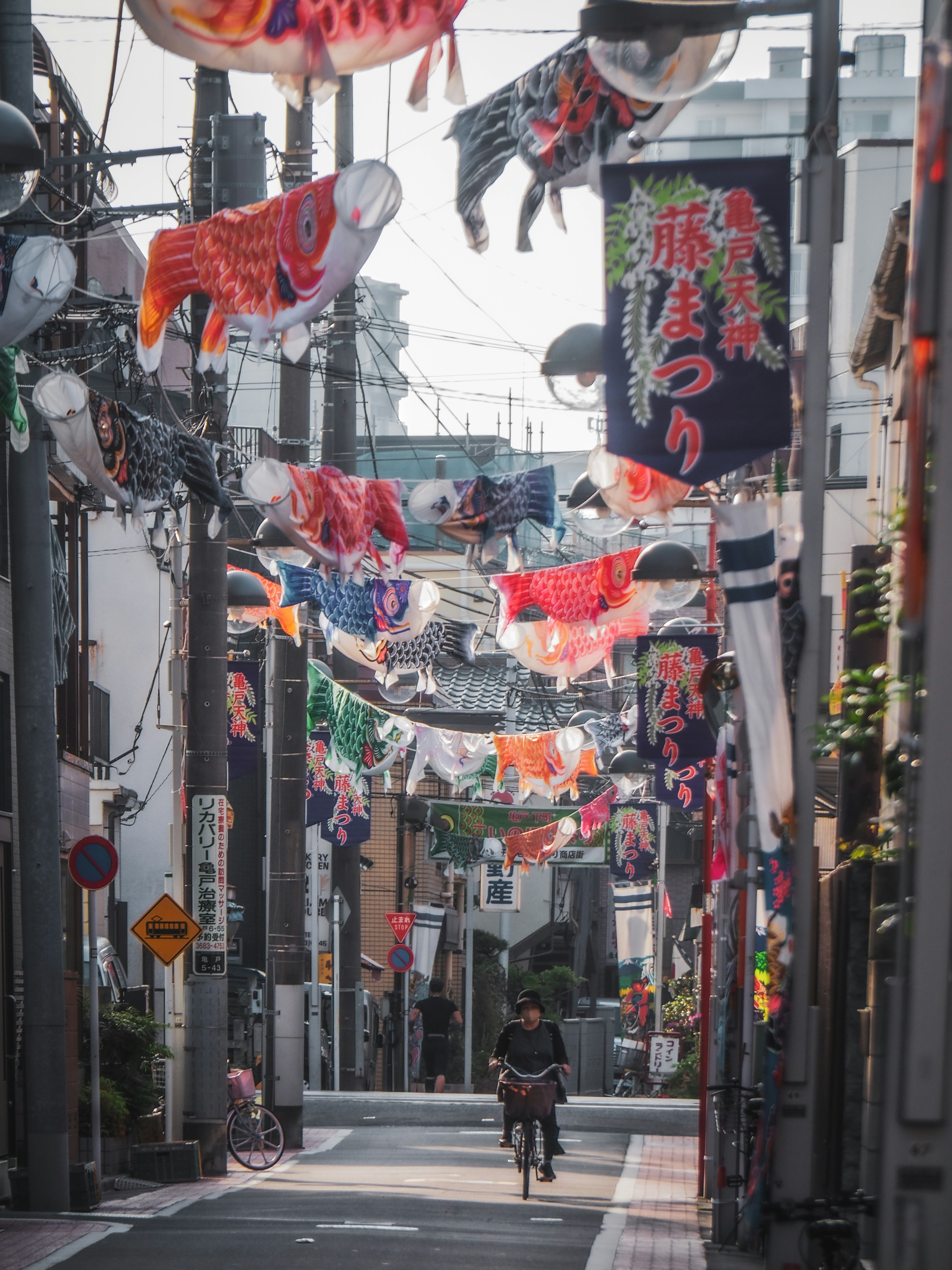 A person riding a bicycle through a Japanese street adorned with colorful lanterns