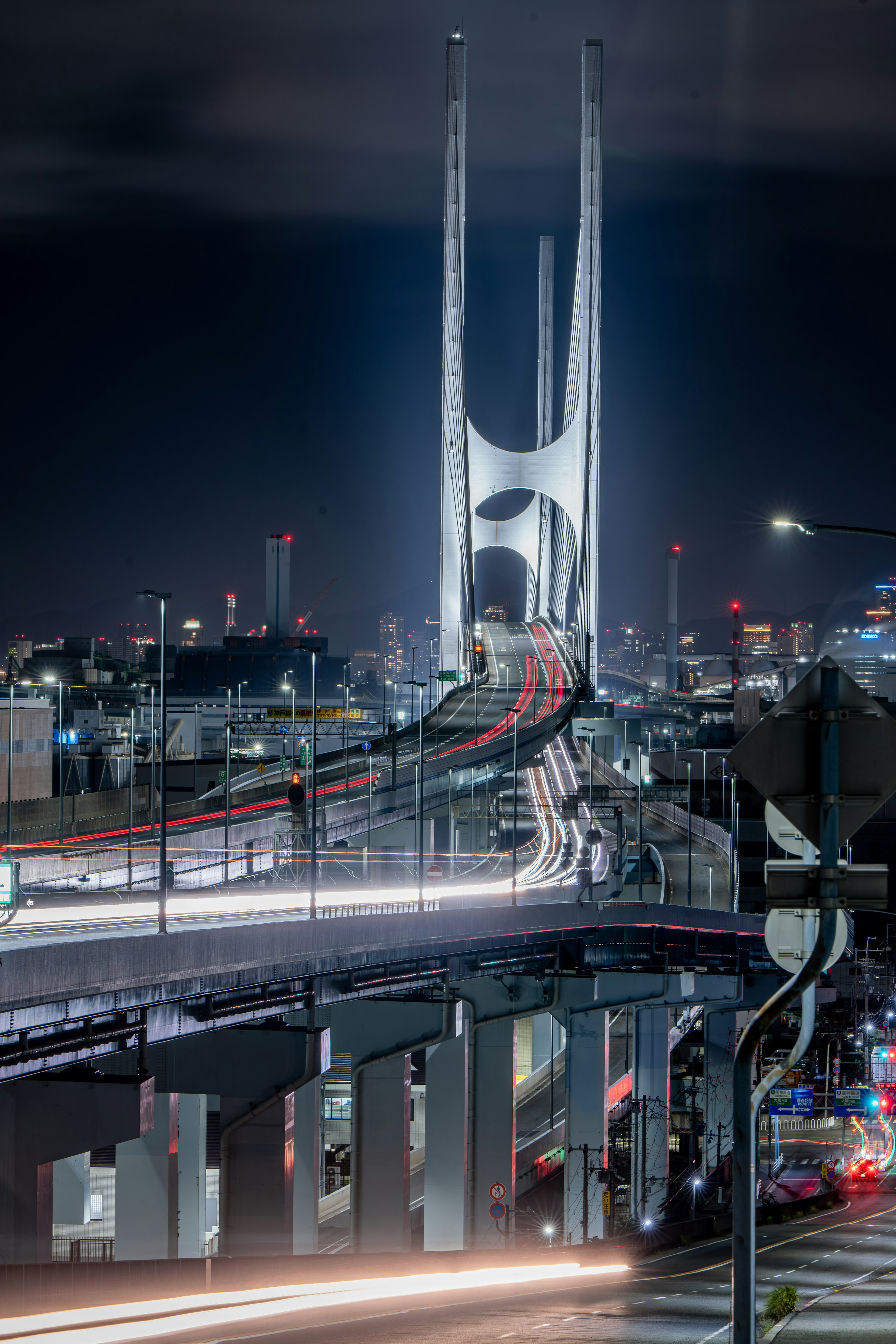 Innovative design bridge towering over urban scenery at night with flowing car lights