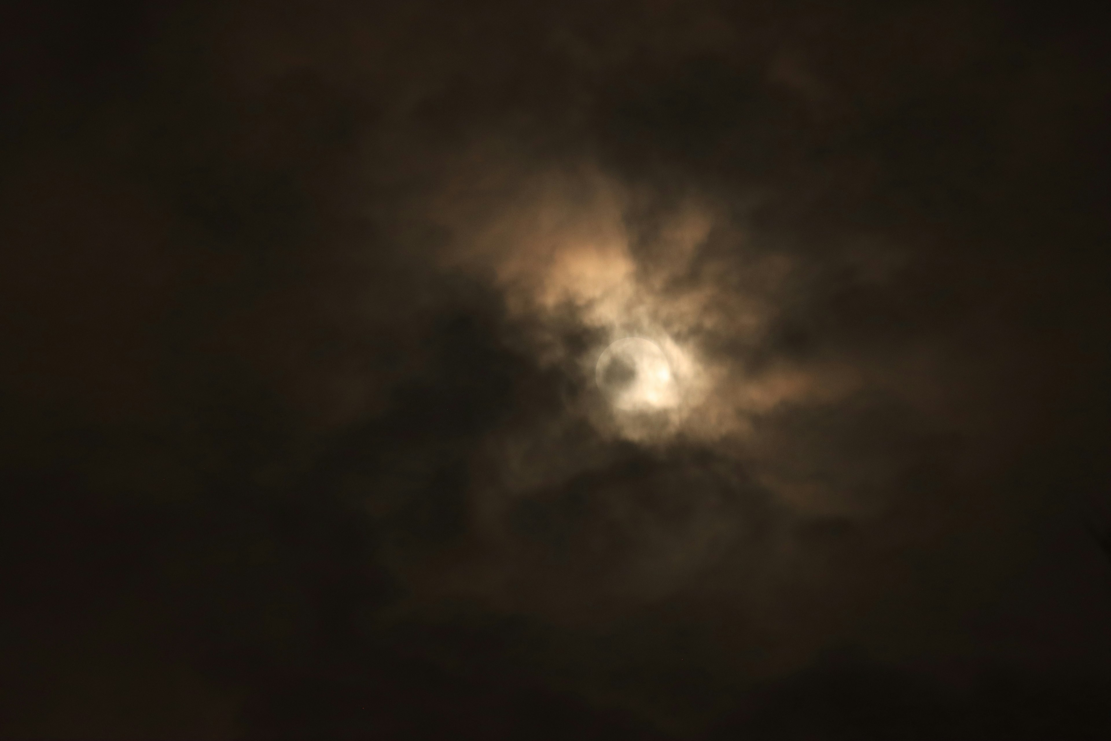 Luna asomando entre nubes oscuras en el cielo nocturno