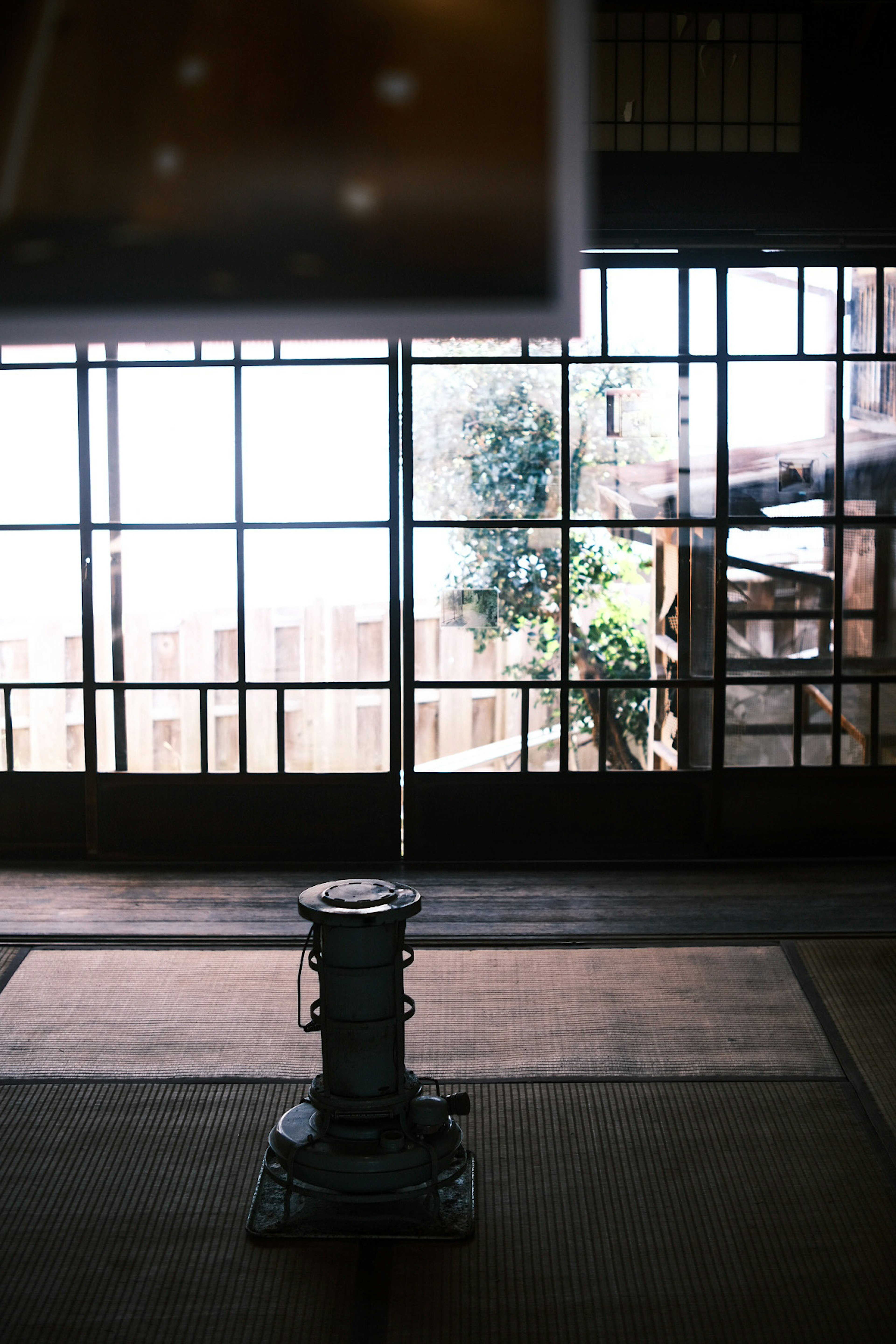 Interior japonés tradicional con una estufa y luz que entra por grandes ventanas