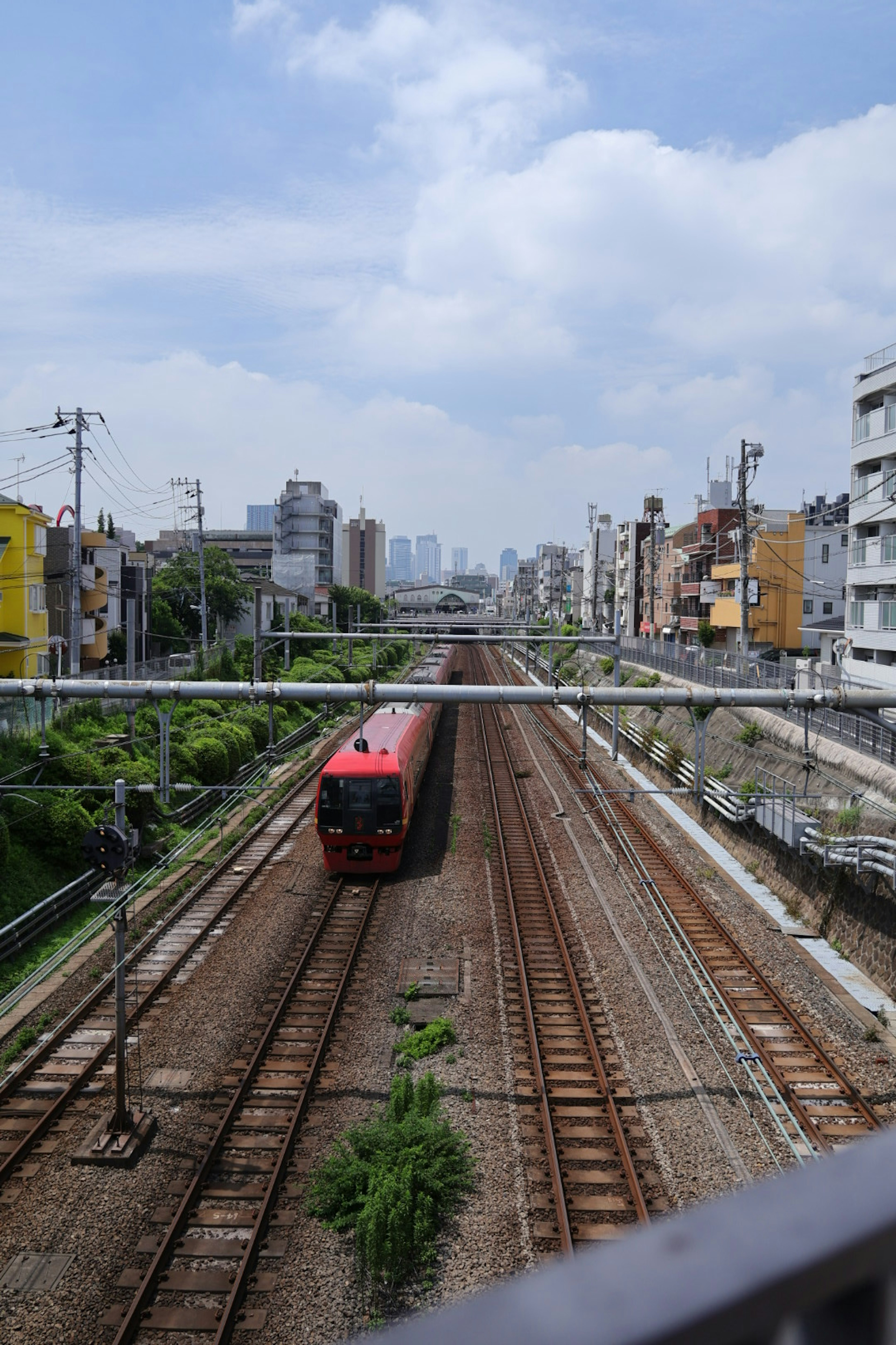 赤い電車が線路を走る都市の風景