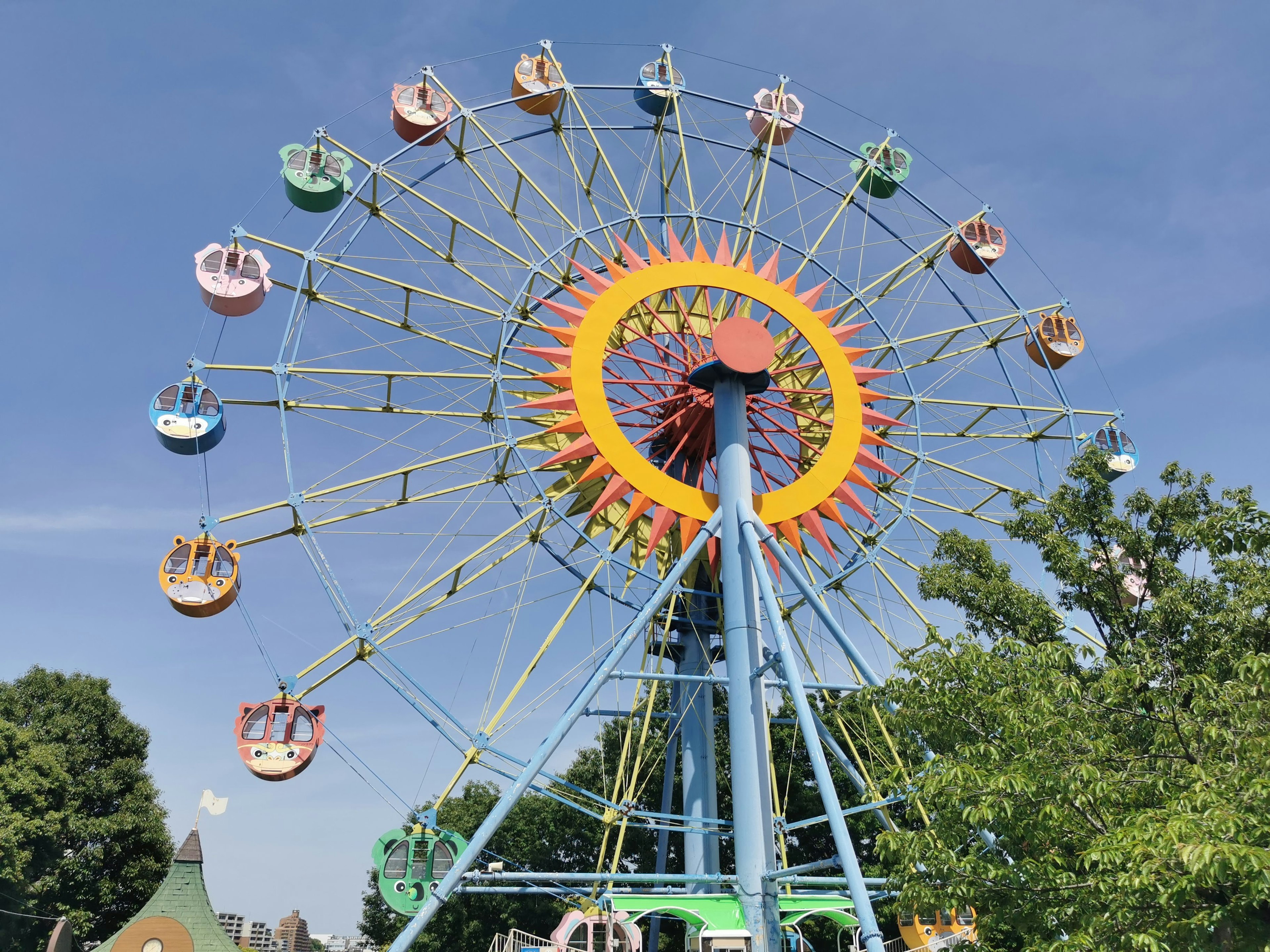 Ruota panoramica colorata che gira sotto un cielo blu in un parco