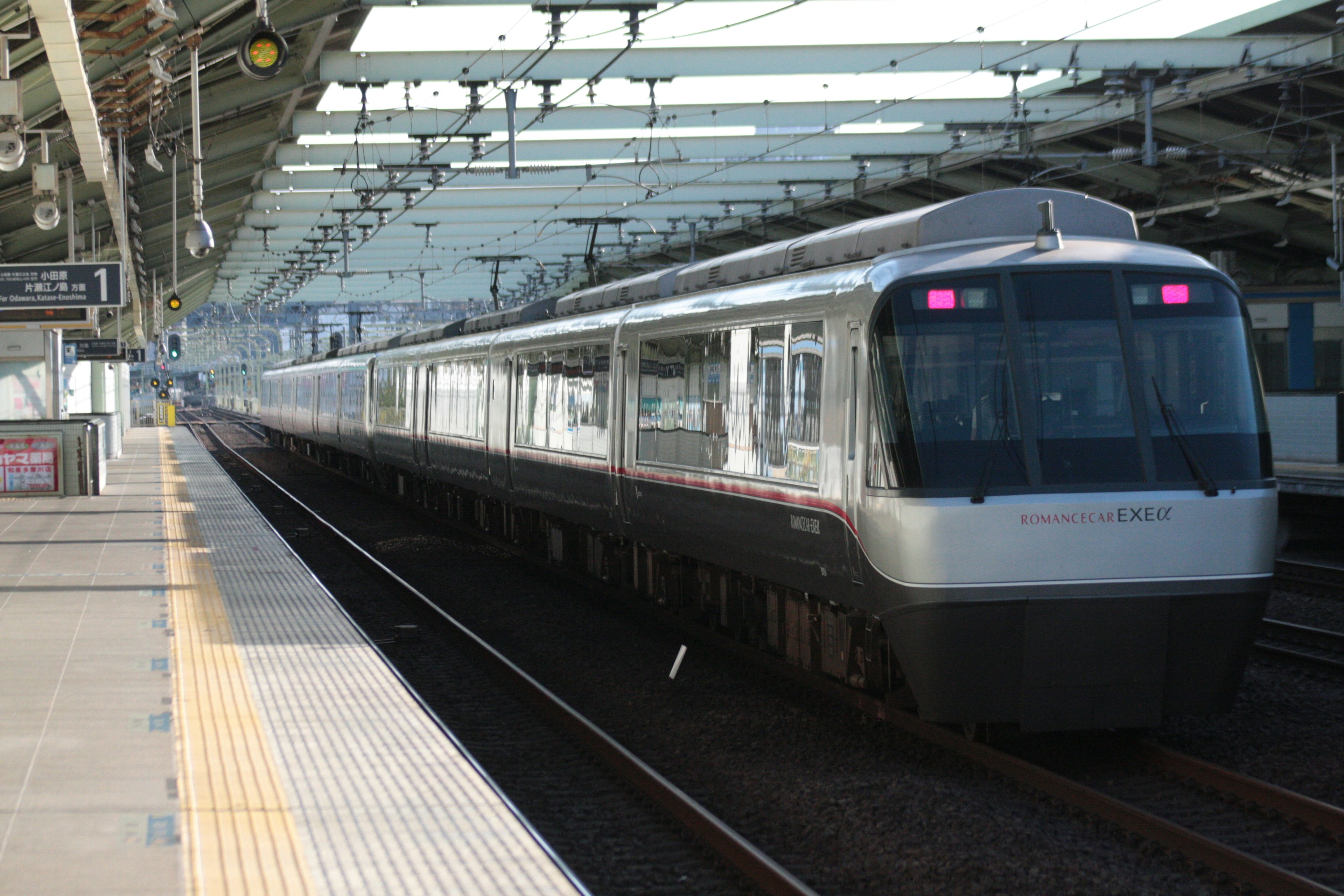 Modern train stopped at a station under a bright roof with railway platform