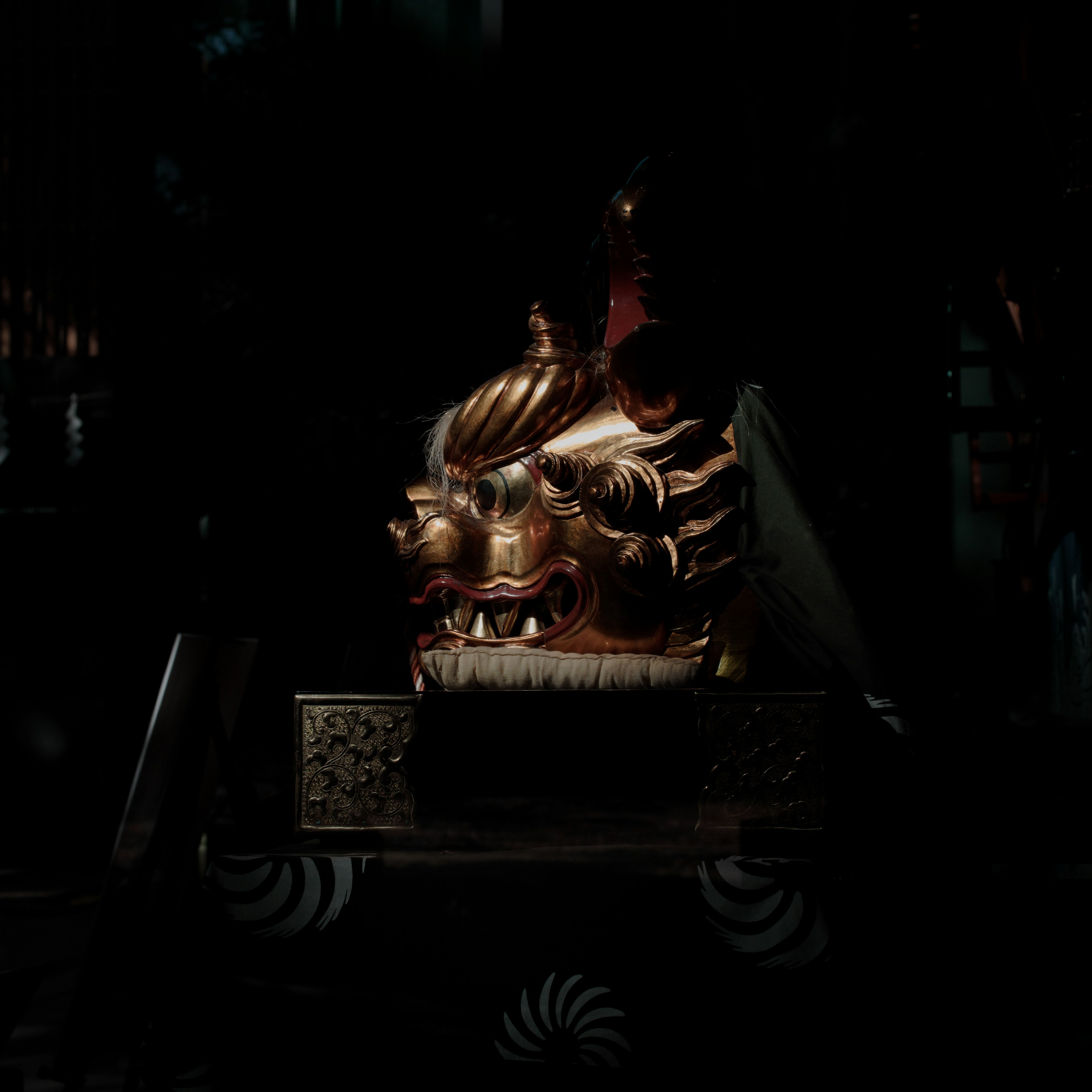 Golden lion head sculpture illuminated against a dark background