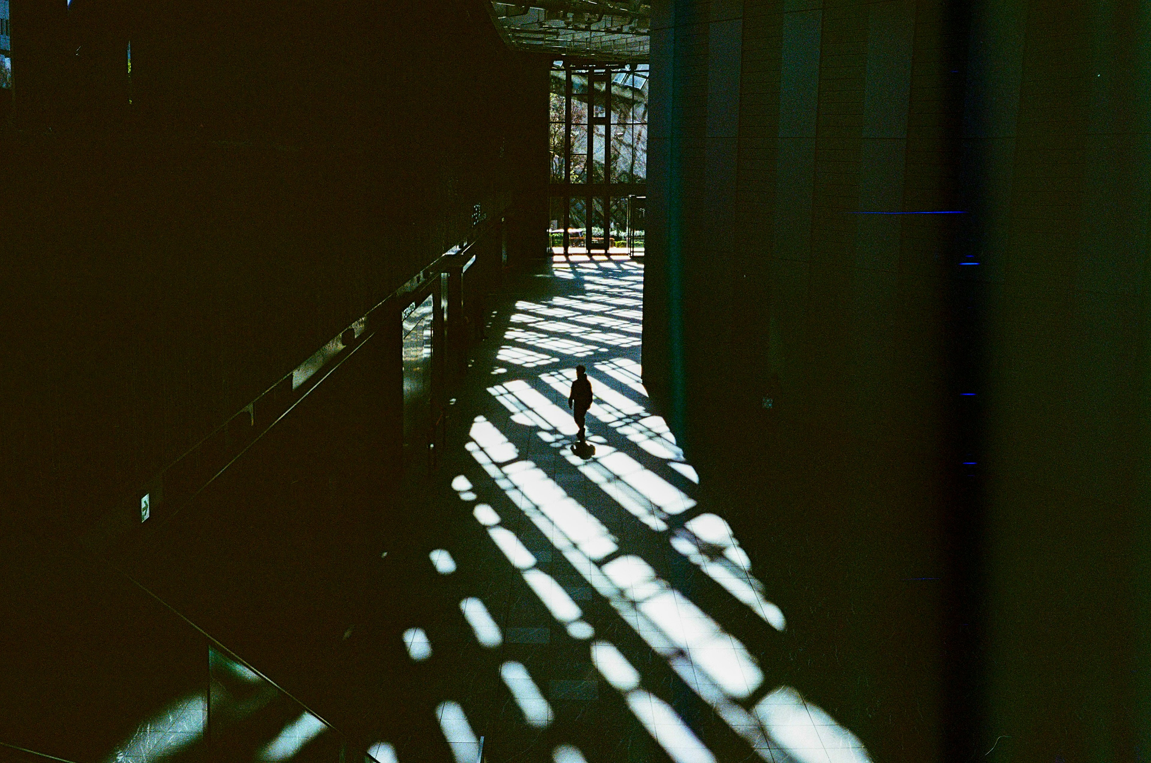 A small object standing in a narrow passage with striped shadows