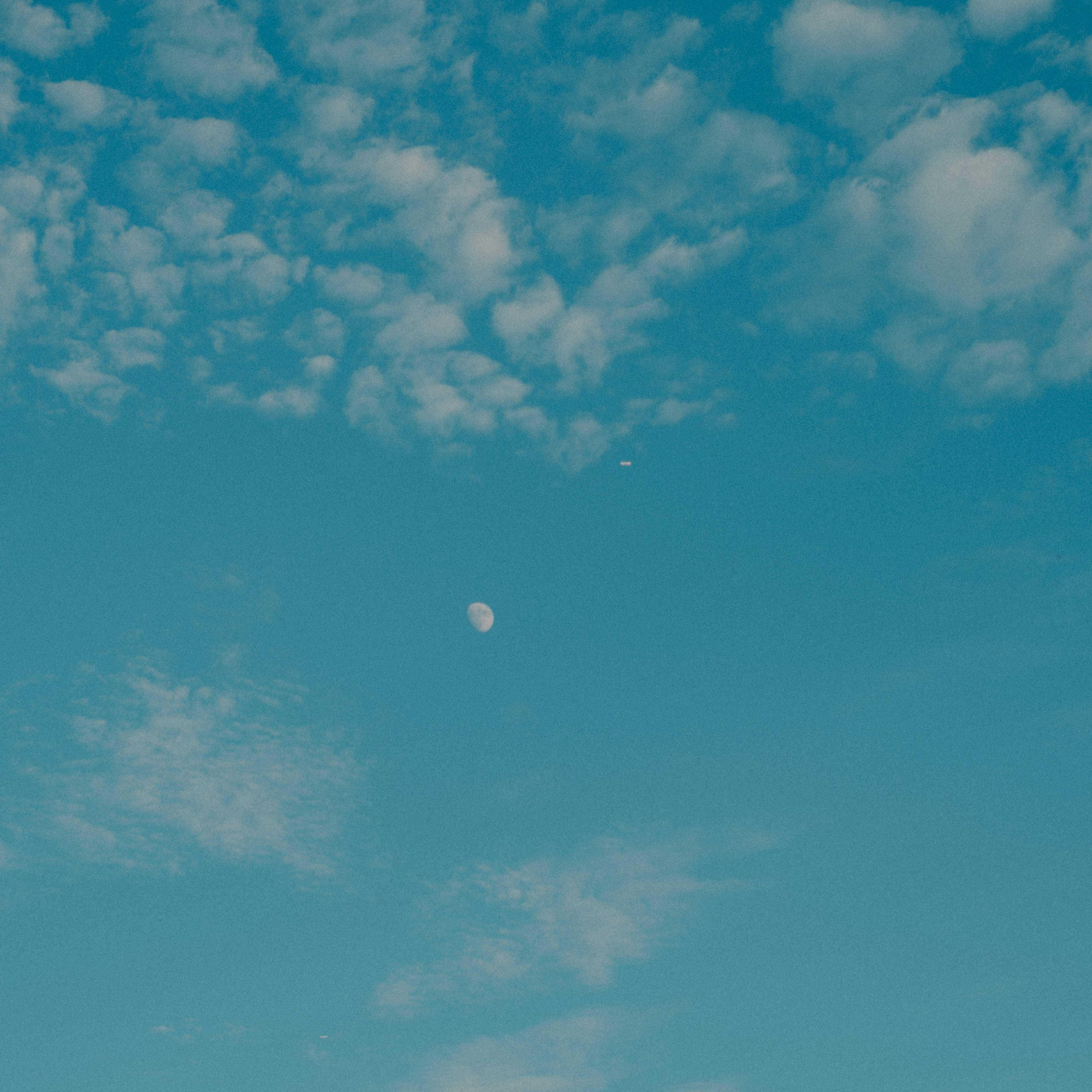 Clouds and moon in a clear blue sky