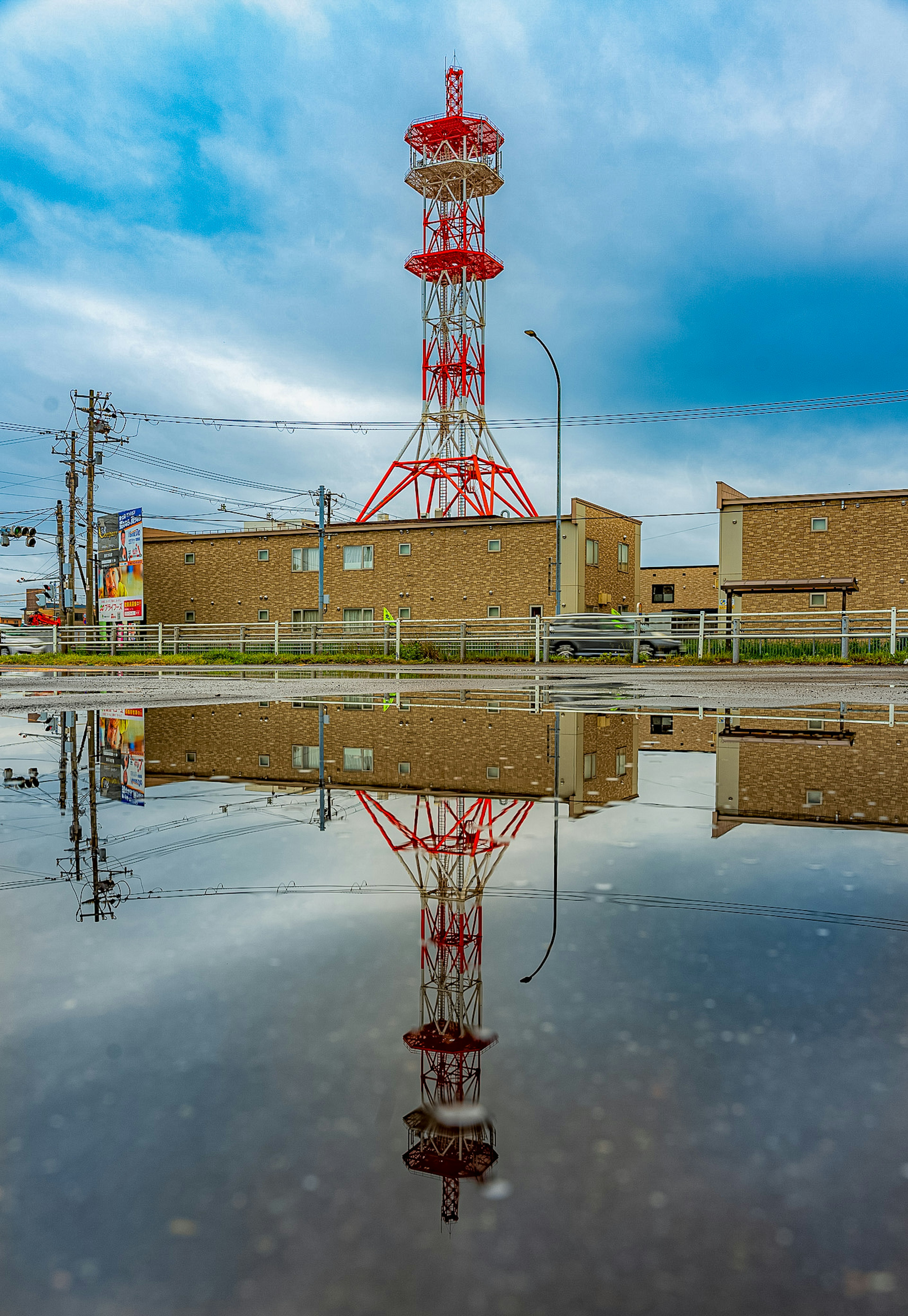 赤い塔とその反射が水たまりに映る風景