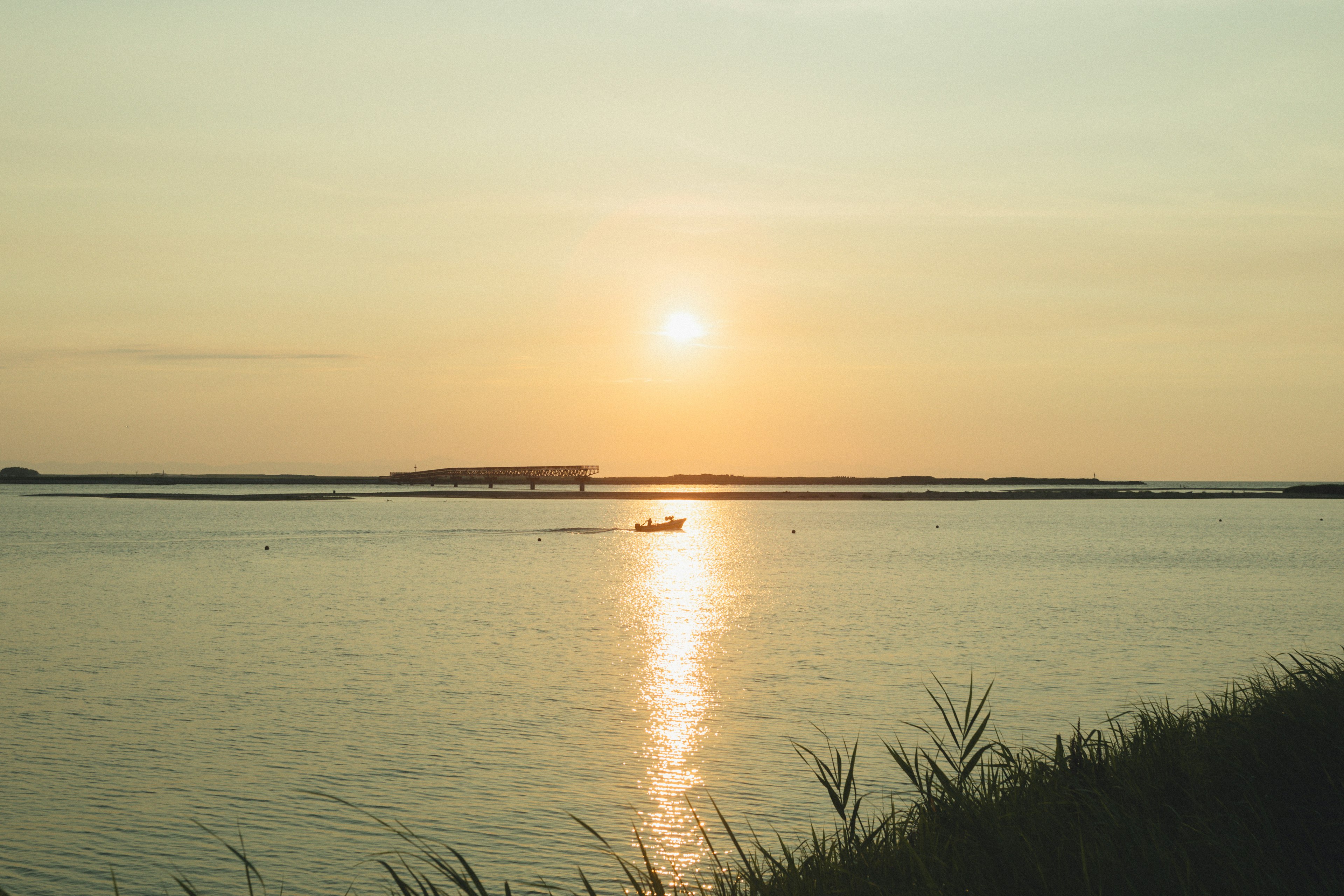 Malersicher Blick auf einen Sonnenuntergang über ruhigem Wasser mit einem kleinen Boot