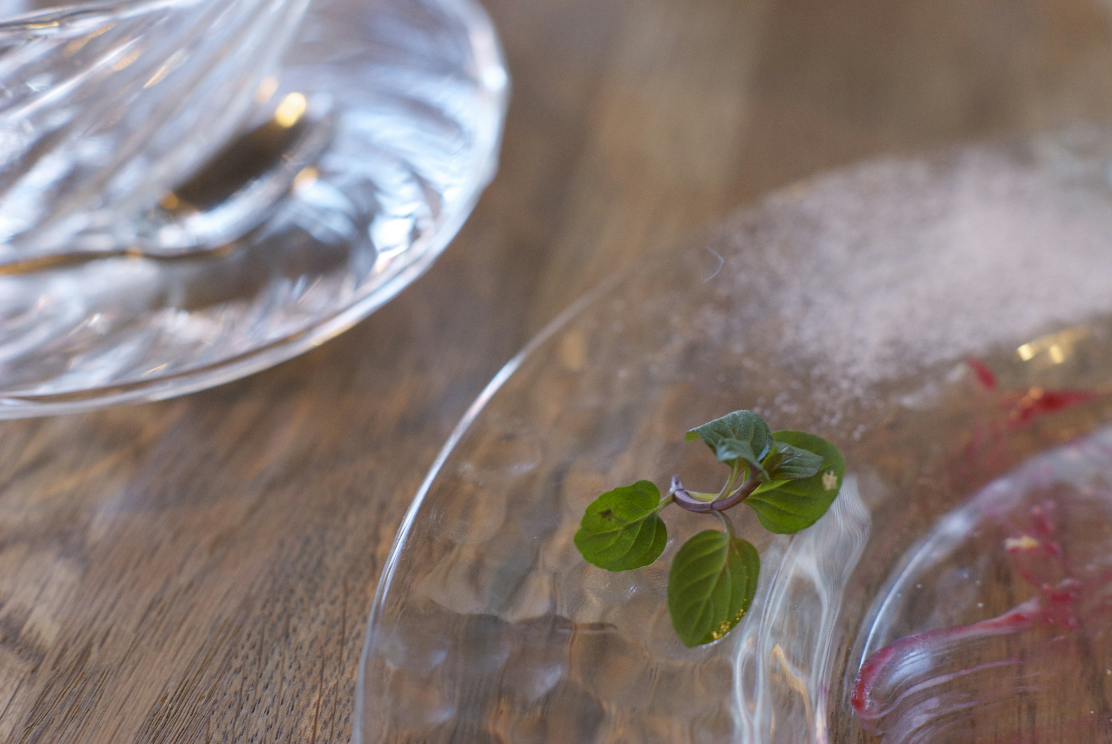 Fresh herbs on a clear plate with a wooden table background