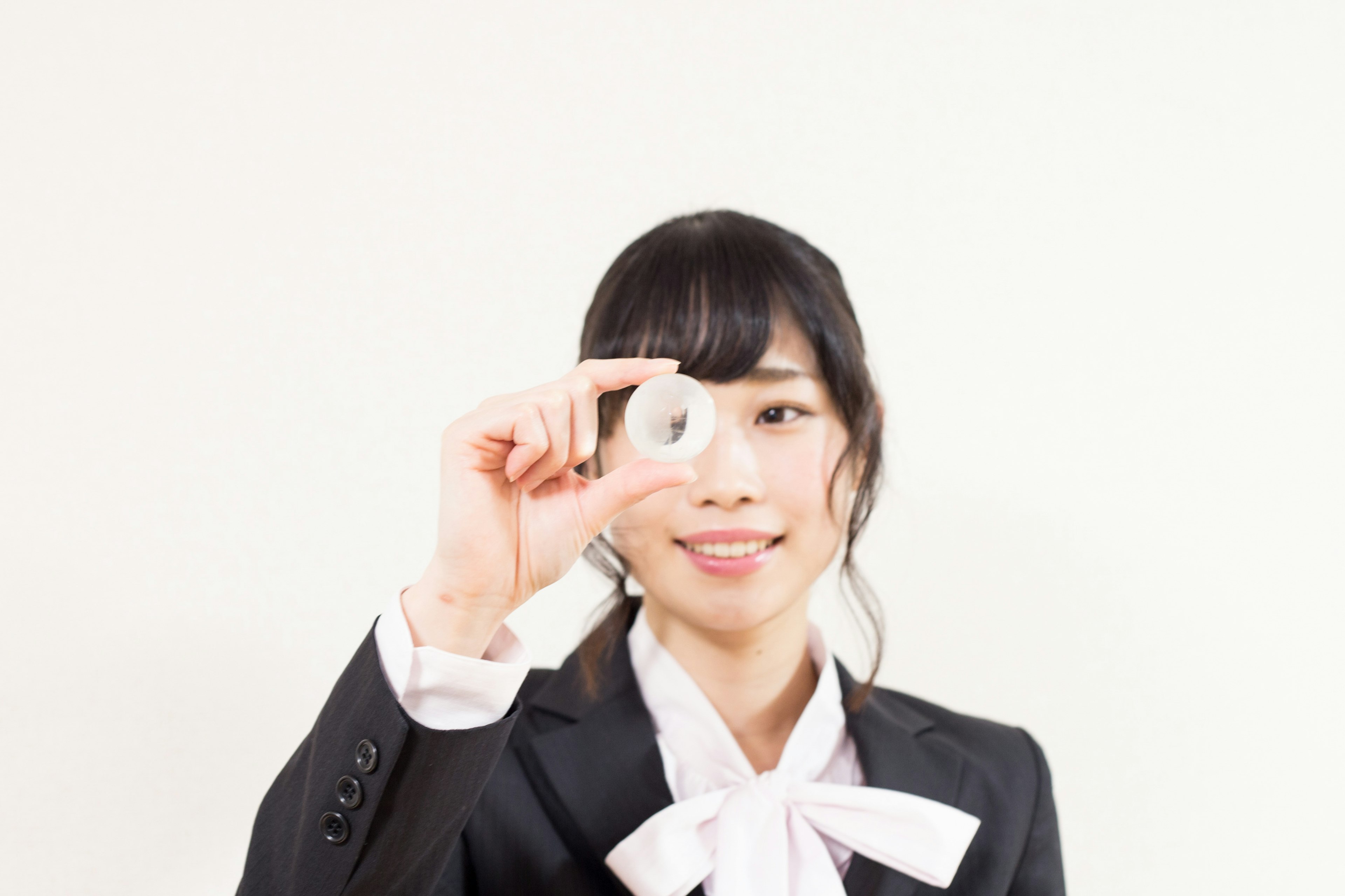 Woman holding a small circular object in front of a white background