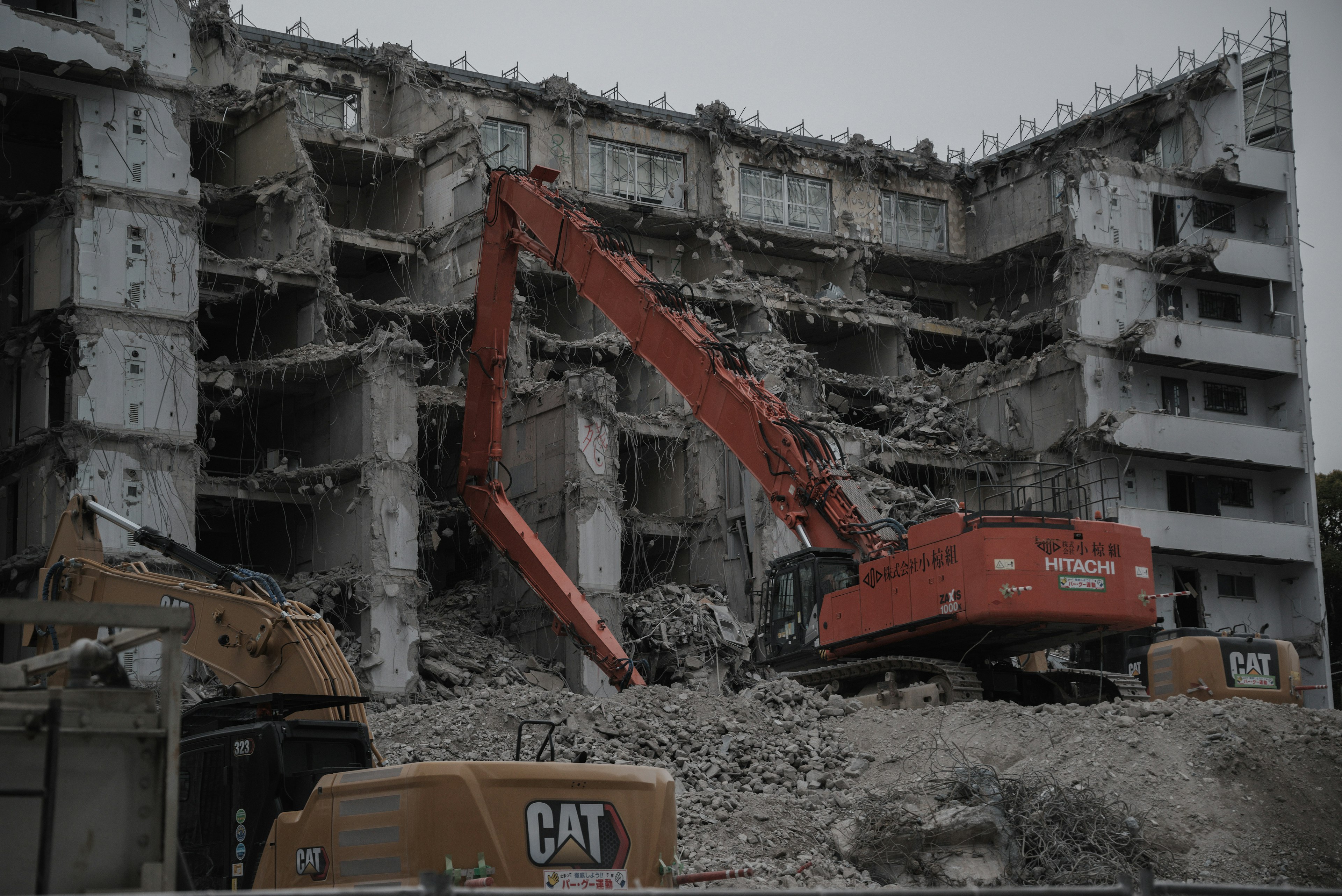 Edificio demolito con un escavatore arancione in azione