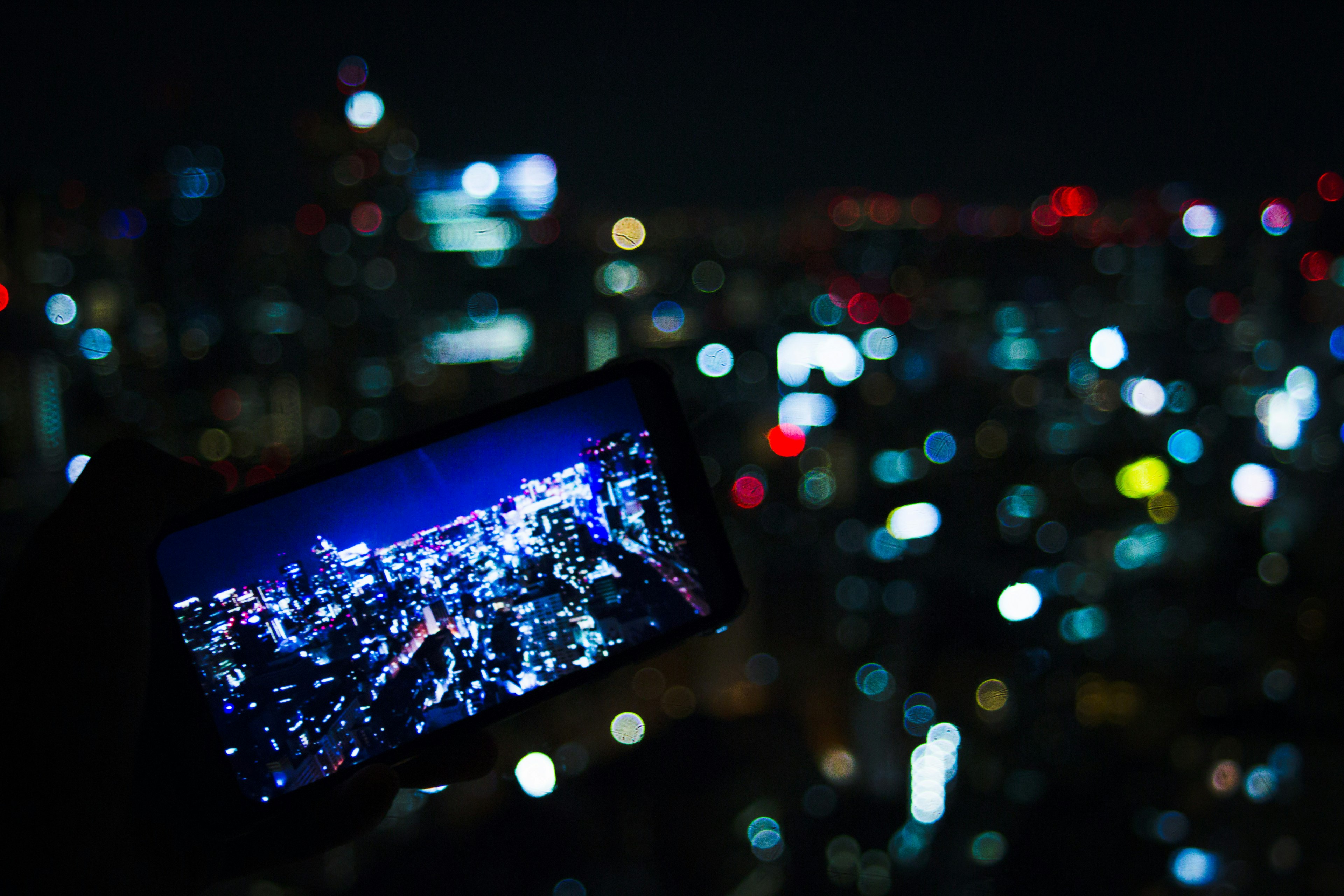 Smartphone capturando el horizonte urbano de noche con luces borrosas