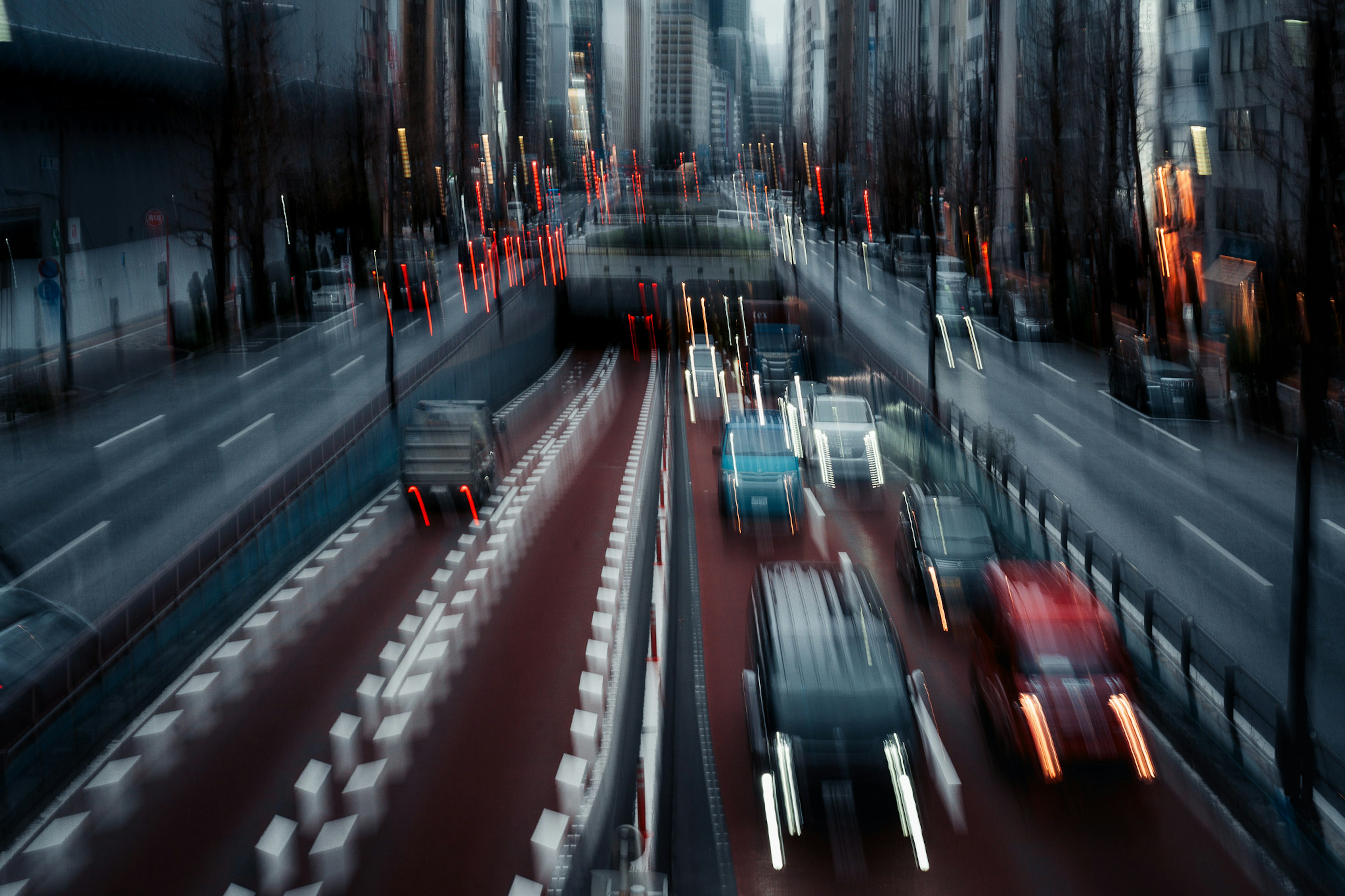 ぼやけた都市の通りでの車の流れと高層ビルの背景