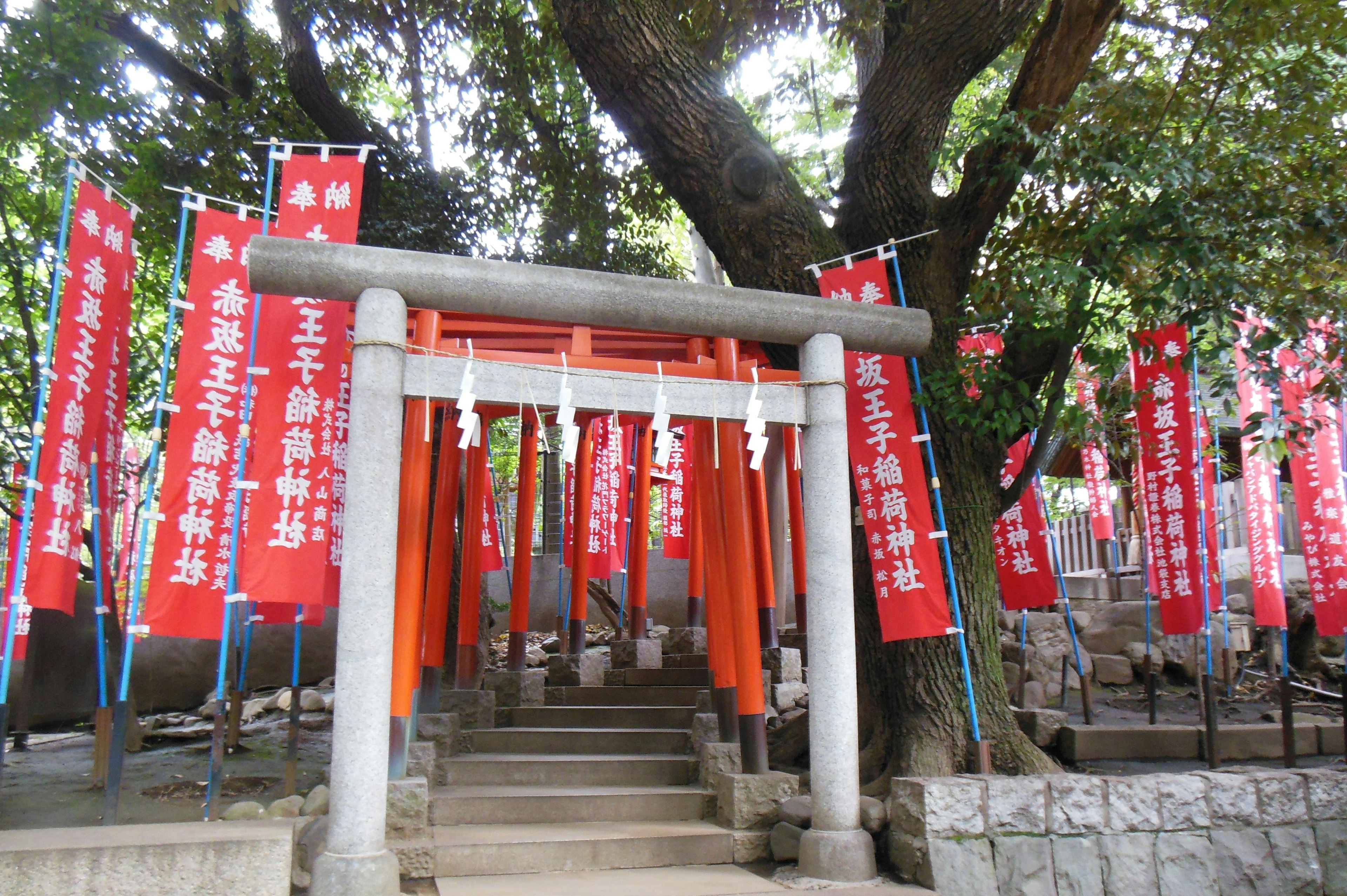 Gerbang torii dengan spanduk merah dan tangga batu di sebuah kuil