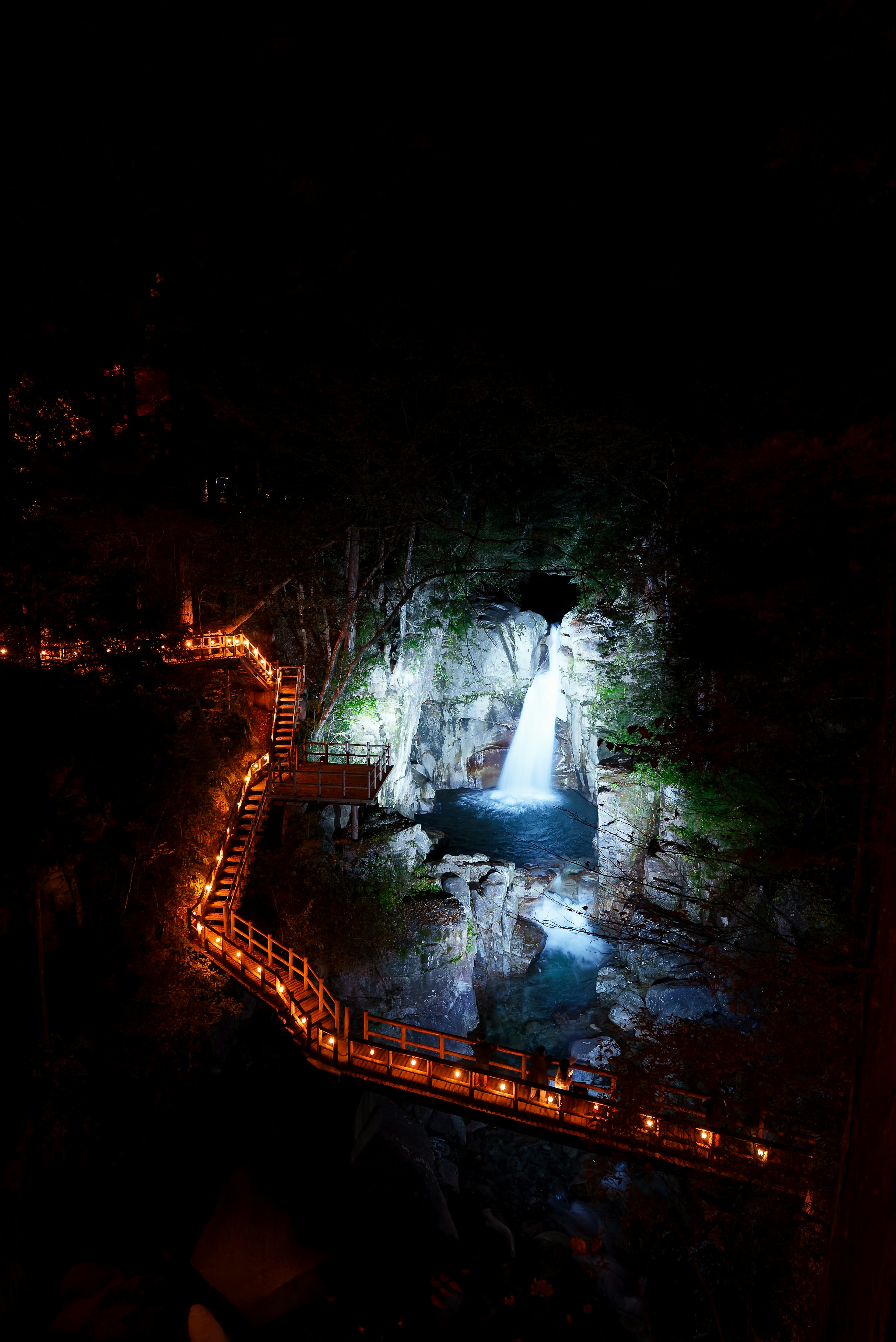 Vista spettacolare di una cascata illuminata di notte con un sentiero illuminato