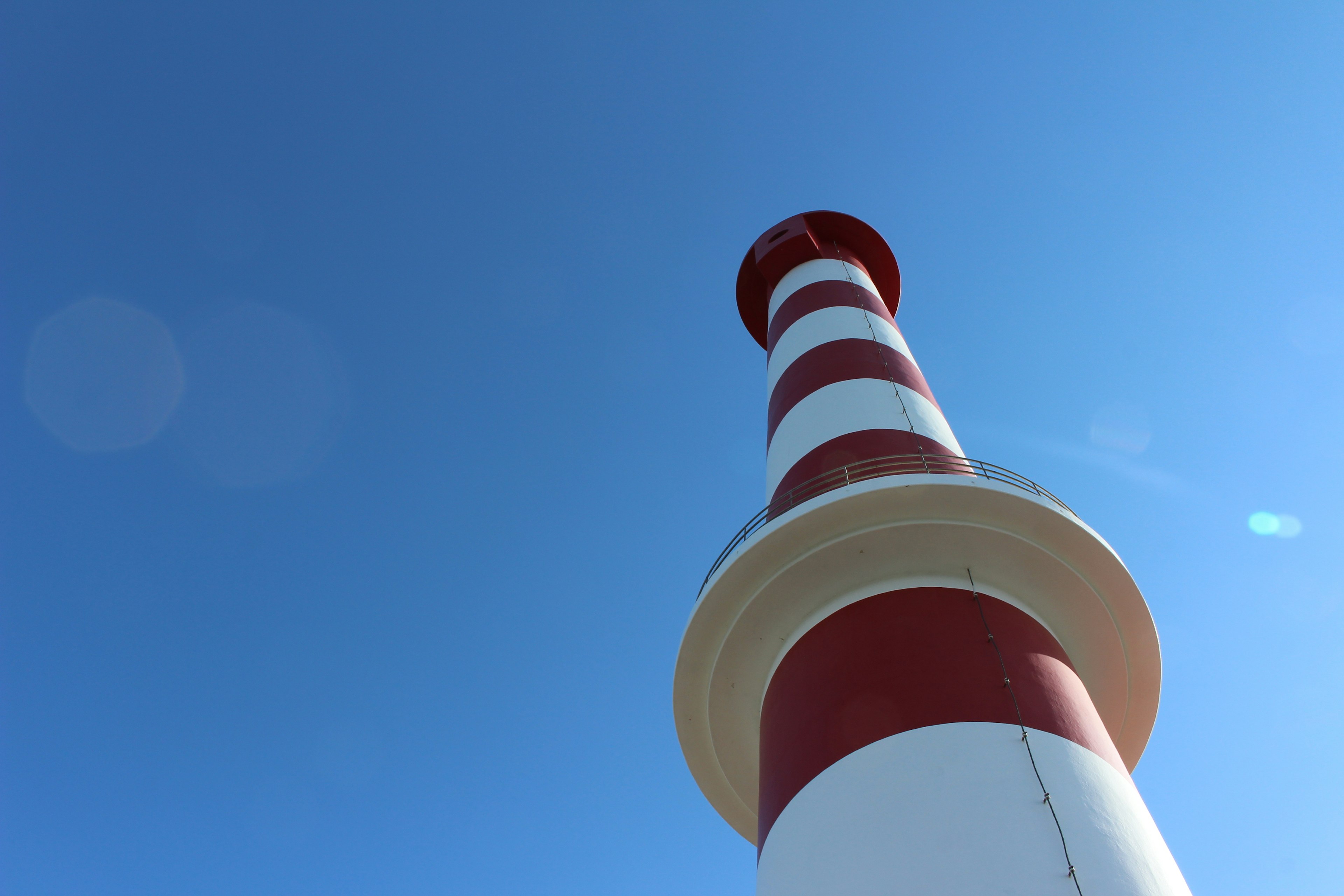 A red and white striped lighthouse standing against a clear blue sky