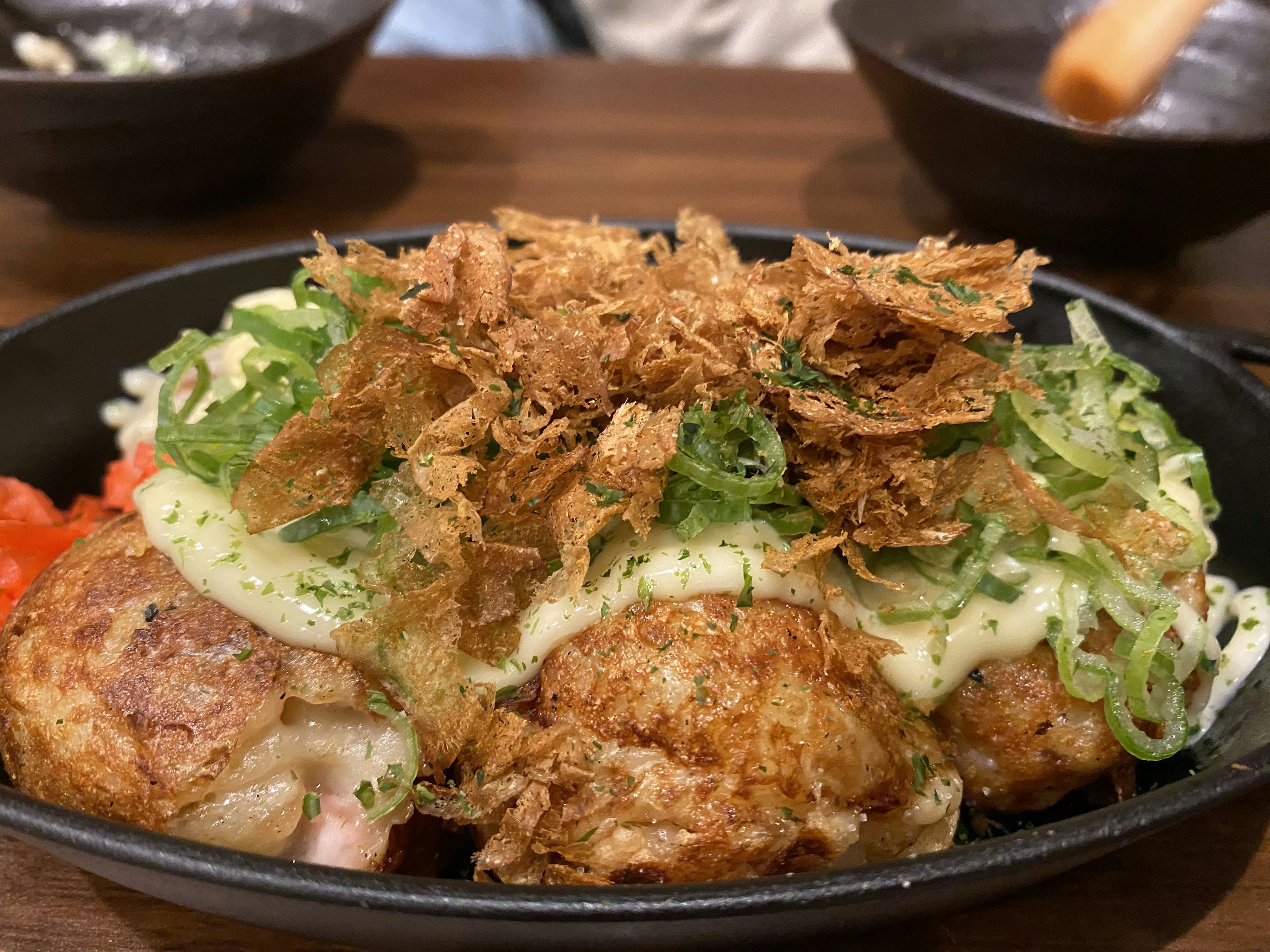 Takoyaki servi sur une plaque chaude garni d'oignons verts et de mayonnaise