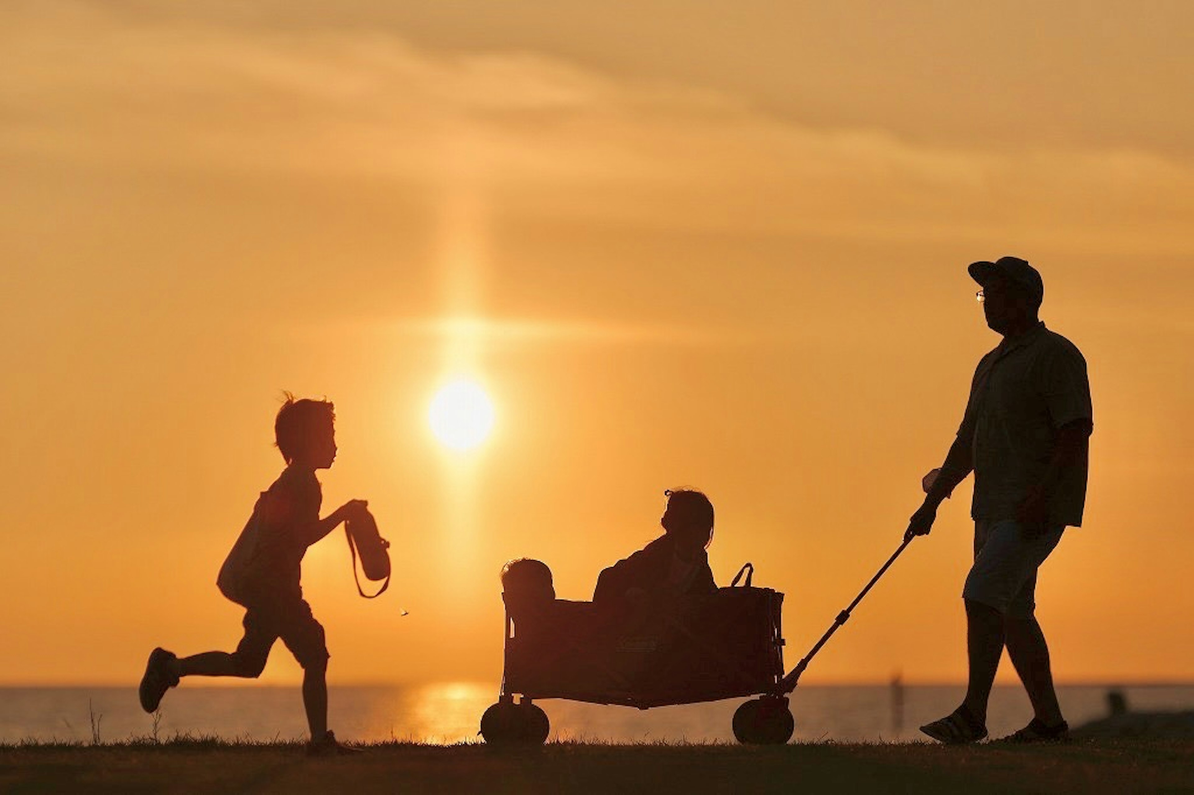 Silhouette d'un père et d'enfants jouant contre un coucher de soleil