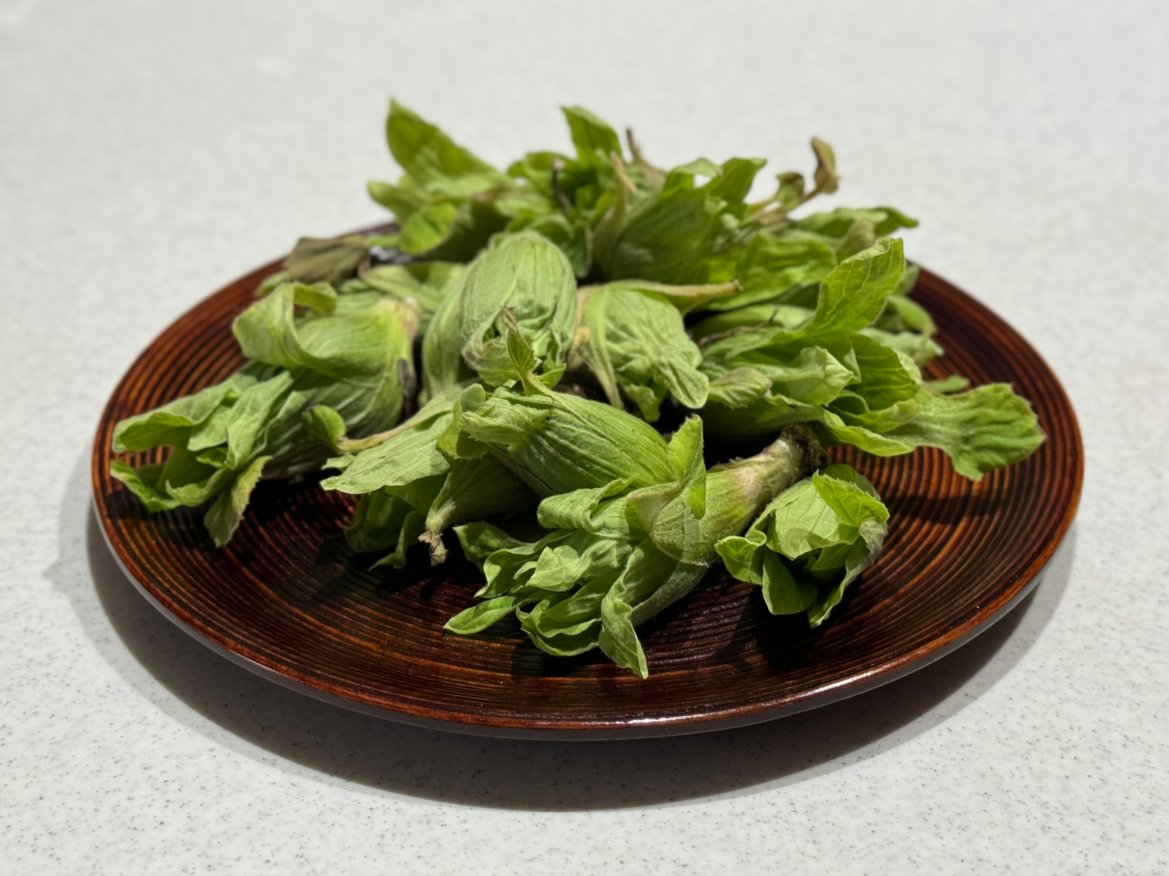 A bunch of fresh green vegetables on a wooden plate