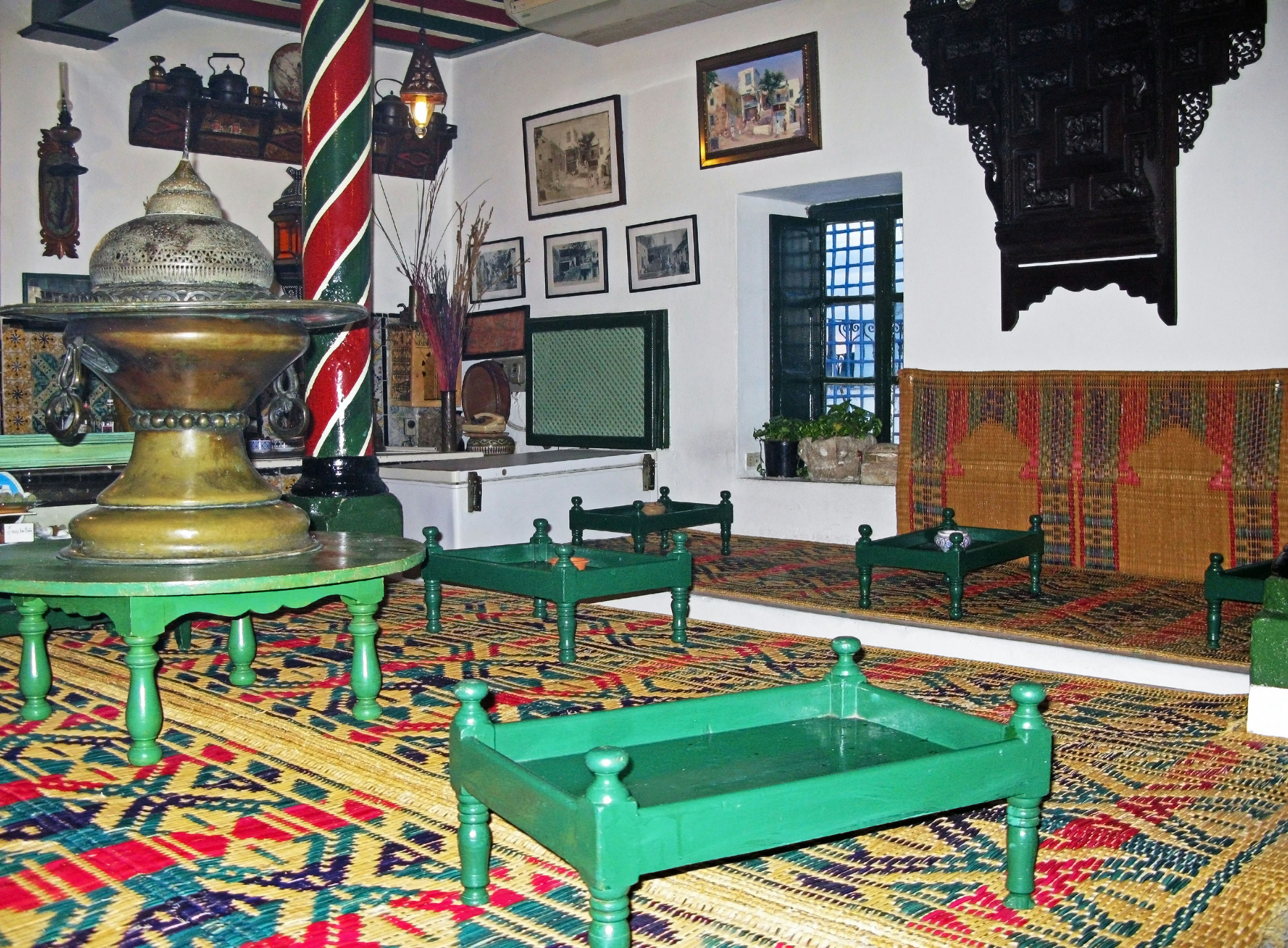 Interior de habitación tradicional con muebles verdes y alfombra estampada